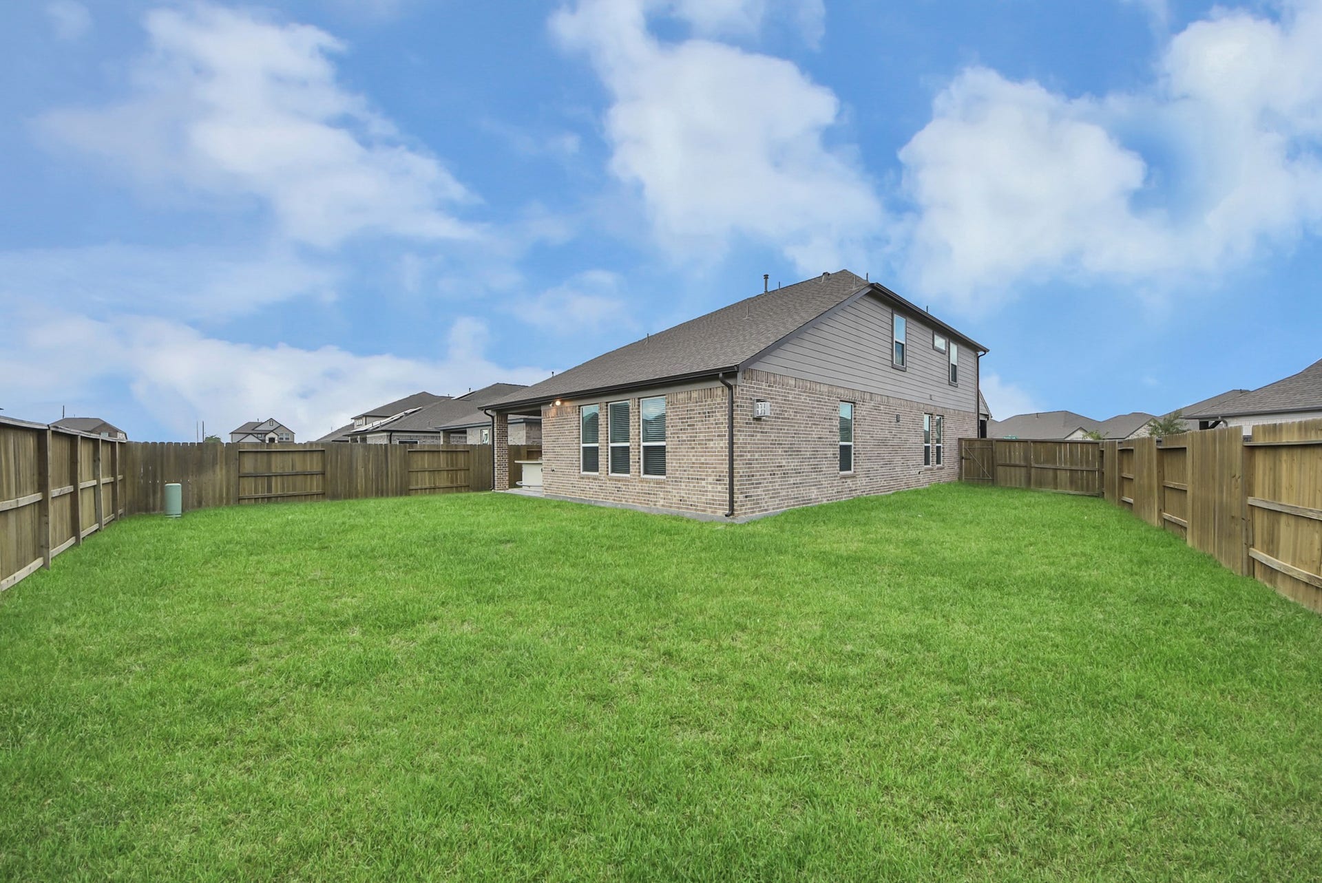 Spacious backyard enclosed by a sturdy wooden fence, offering ample room for outdoor activities and gardening. The two-story brick home provides a charming and durable exterior.