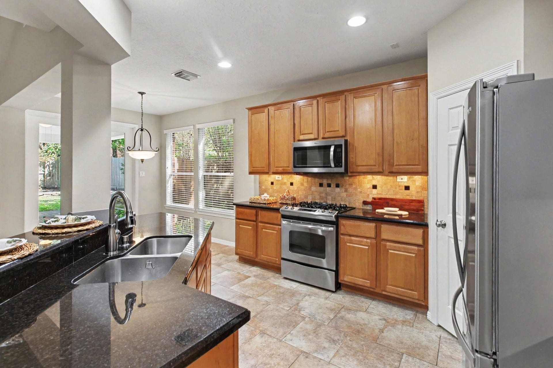 42 S Peaceful Canyon Circle, The Woodlands, TX 77381 Gorgeous kitchen with granite countertops, stainless steel appliances including a gas range, microwave, dishwasher, and full size refrigerator, under cabinet lighting and an oversized pantry.