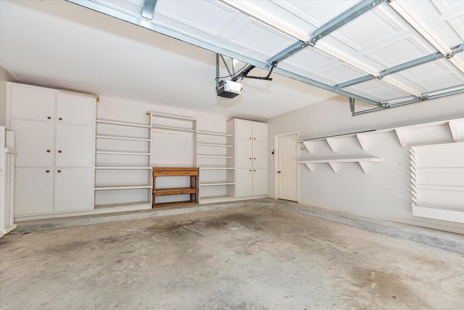 42 S Peaceful Canyon Circle, The Woodlands, TX 77381 A view of this spacious and useful garage with multiple built-ins, shelves, a workbench, and an automatic garage door opener. It even has a billiard table cue stick holder for those that love the game of pool!