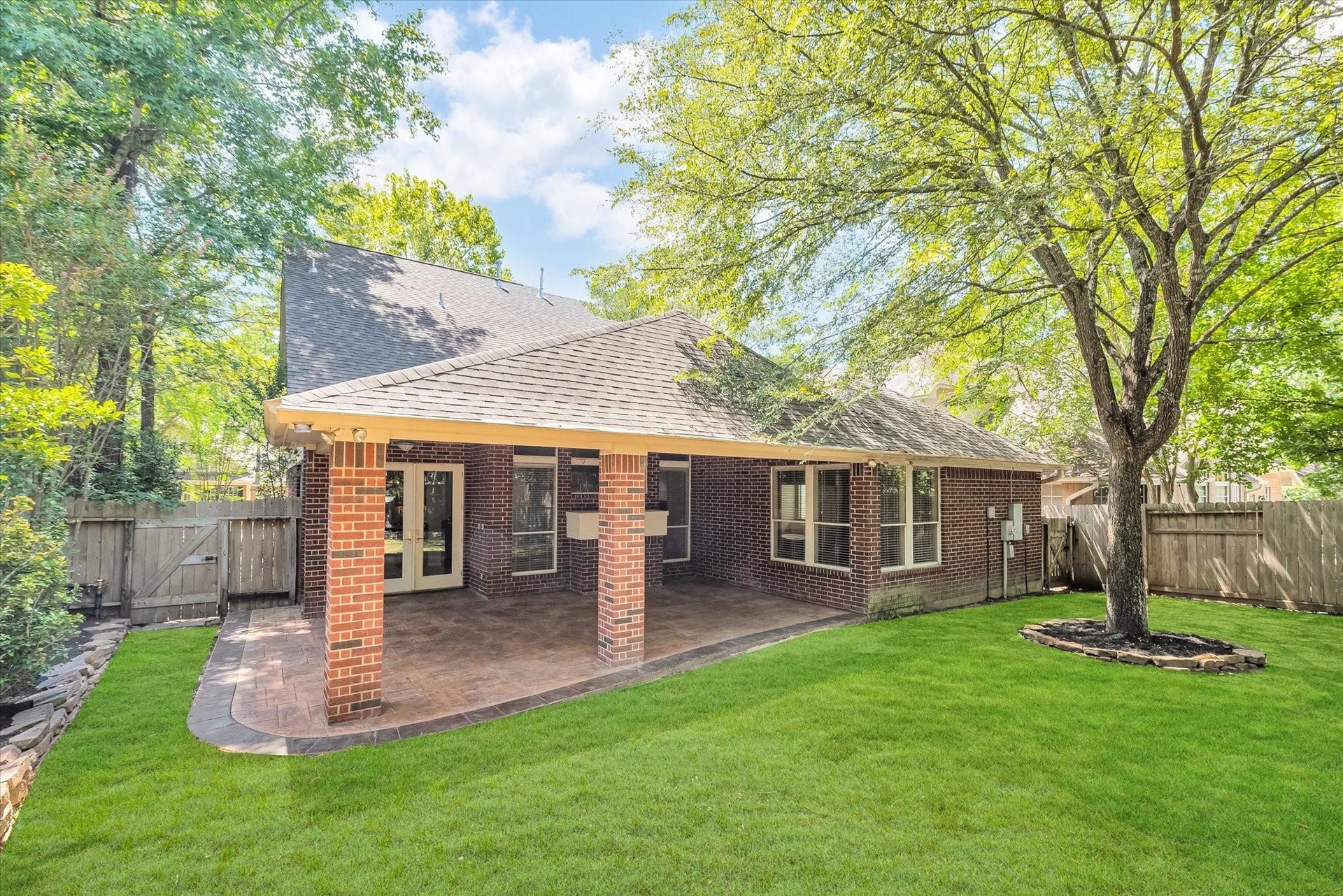 42 S Peaceful Canyon Circle, The Woodlands, TX 77381 Back elevation of the home showing the beautiful trees and wooded aesthetics, lush lawn, and covered back patio.