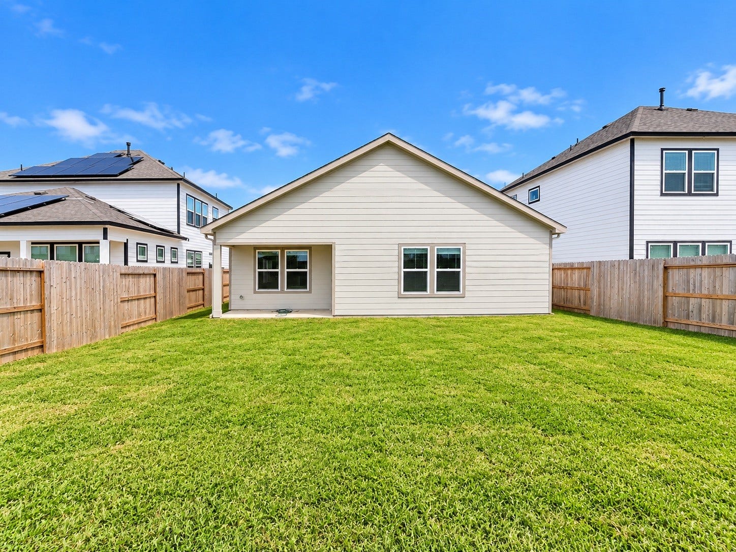 419 Pirate Falls Lane, Crosby, TX 77532 Spacious backyard with well-maintained lawn and a cozy covered patio, perfect for outdoor activities and relaxation.