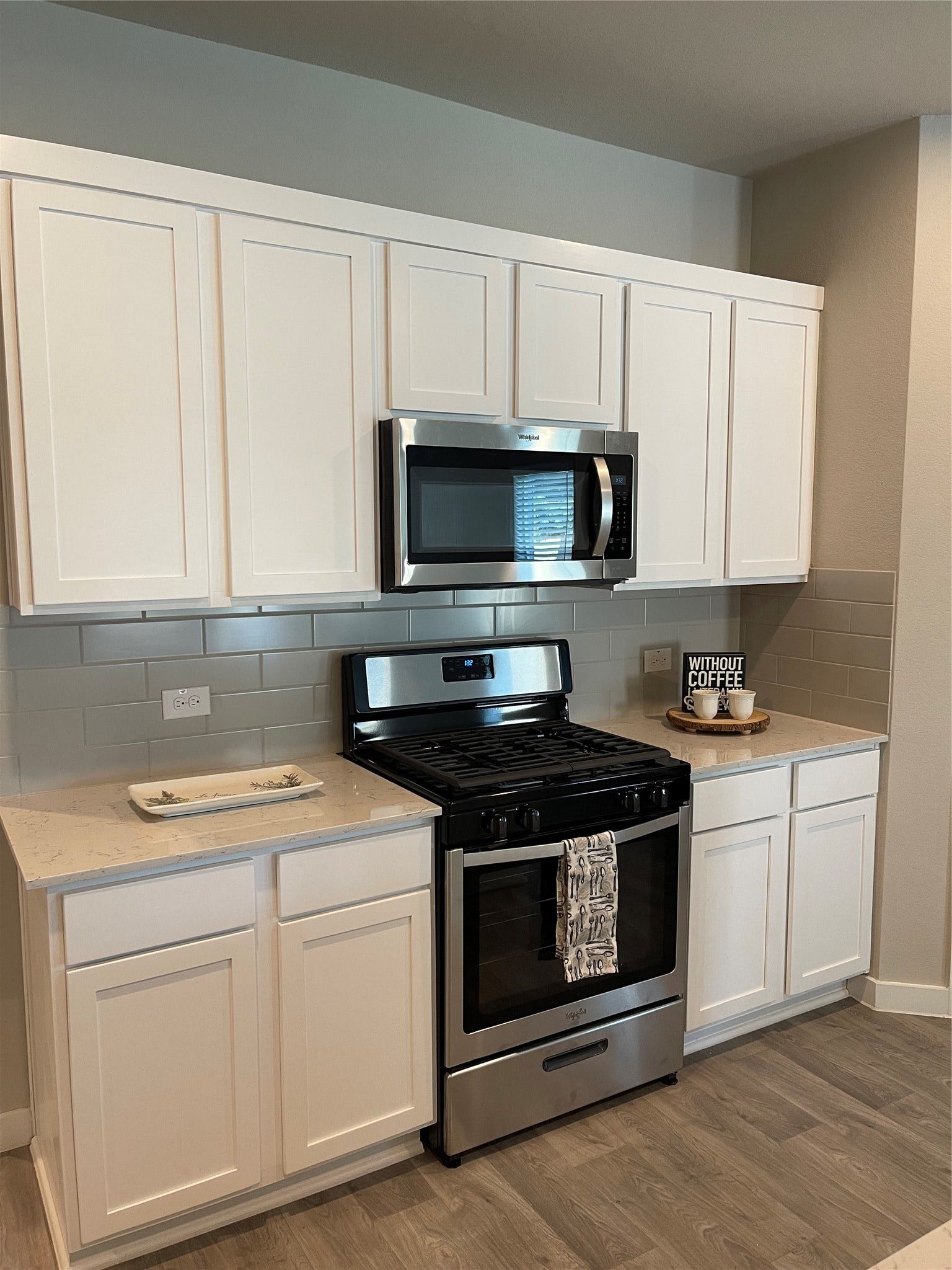 12285 Council Grove Drive, Conroe, TX 77384 Modern kitchen with sleek stainless steel appliances, white cabinetry, and a stylish tile backsplash.