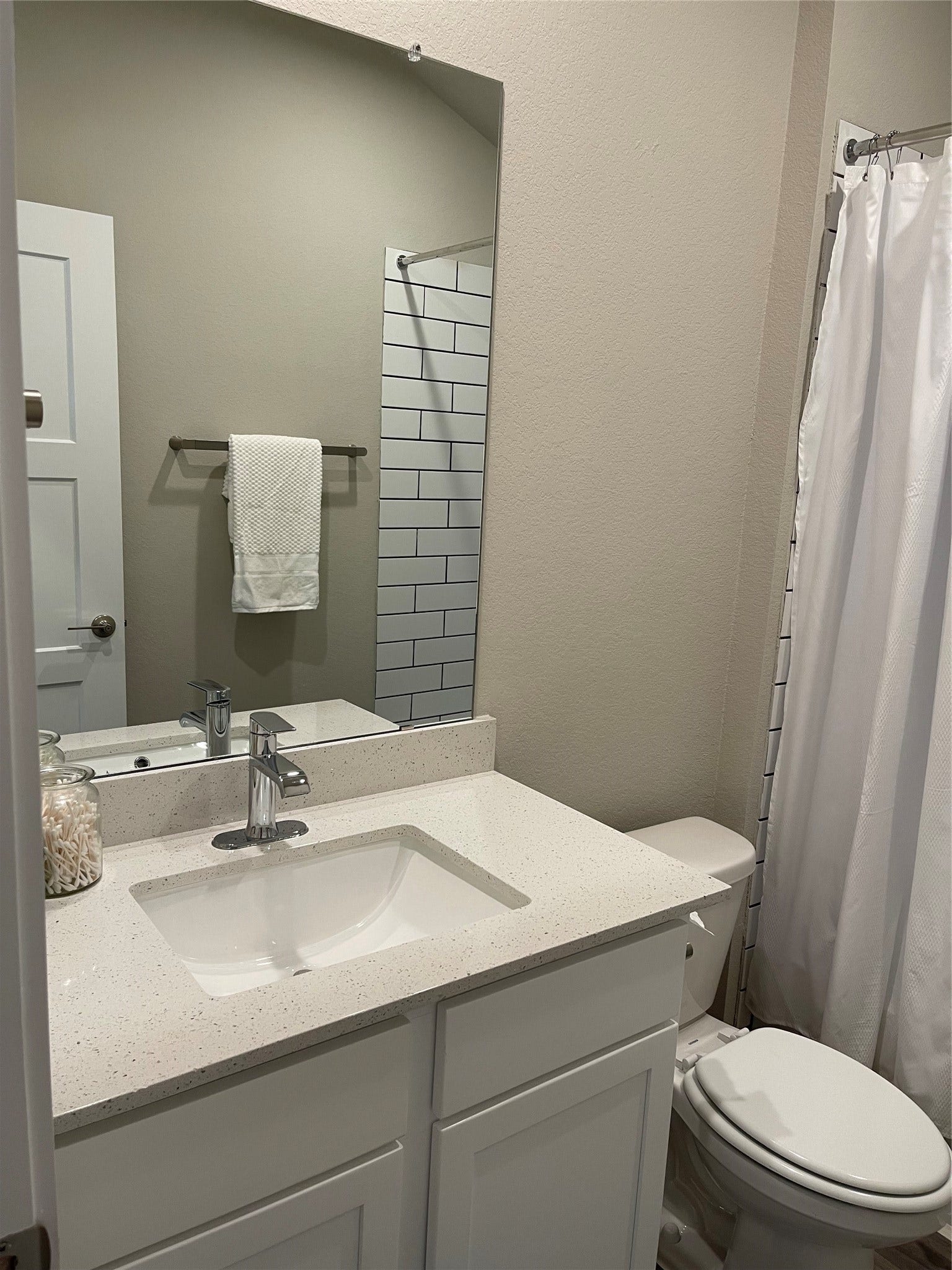 12285 Council Grove Drive, Conroe, TX 77384 Modern bathroom with a sleek vanity, white countertop, and chrome fixtures, featuring a stylish subway tile shower and neutral tones for a clean, inviting look.