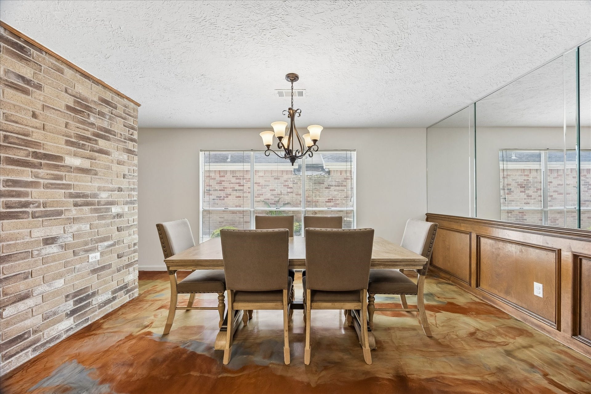 3806 Crystal Falls Drive, Missouri City, TX 77459 Formal dining area with a statement chandelier, large window, custom wood wainscoting, and mirrored accent wall.