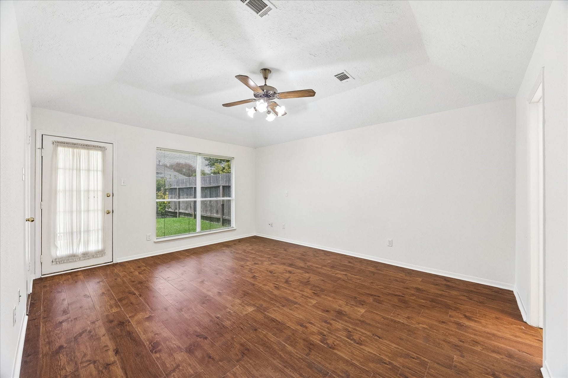 3806 Crystal Falls Drive, Missouri City, TX 77459 Spacious downstairs primary retreat with warm wood flooring, tray ceiling, abundant natural light, and backyard access.