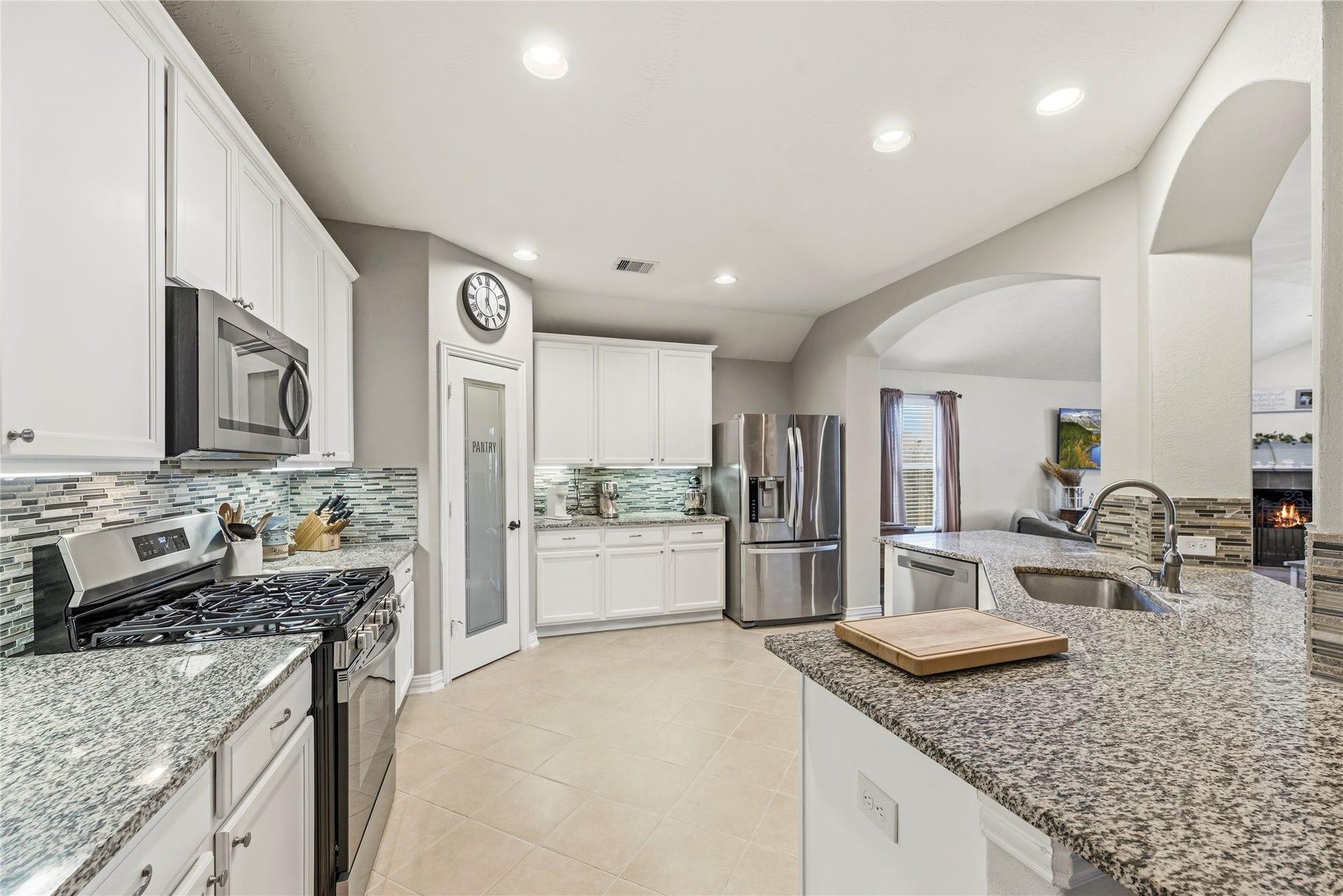 16014 Mark Crest Drive, Hockley, TX 77447 Gorgeous kitchen features granite countertops, glass tile backsplash, white cabinetry, under cabinet lighting, stainless steel appliances and a gas range.