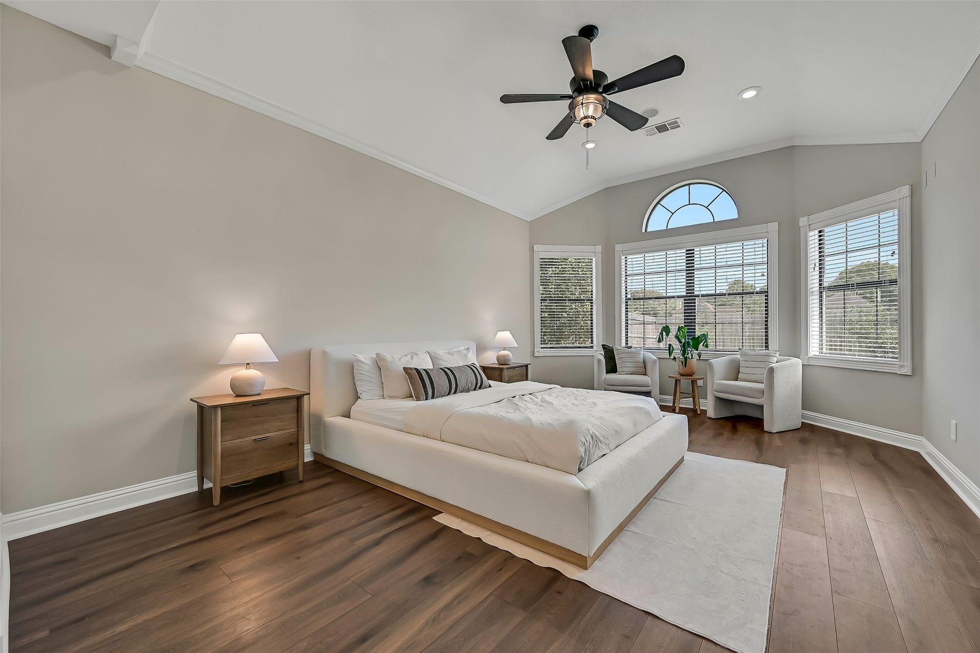 2505 Sarasota Drive, Friendswood, TX 77546 Privately situated on the first floor, the spacious primary retreat features a vaulted ceiling, luxury vinyl plank flooring and a generous bank of windows topped by an arched transom, filling the room with beautiful natural light.