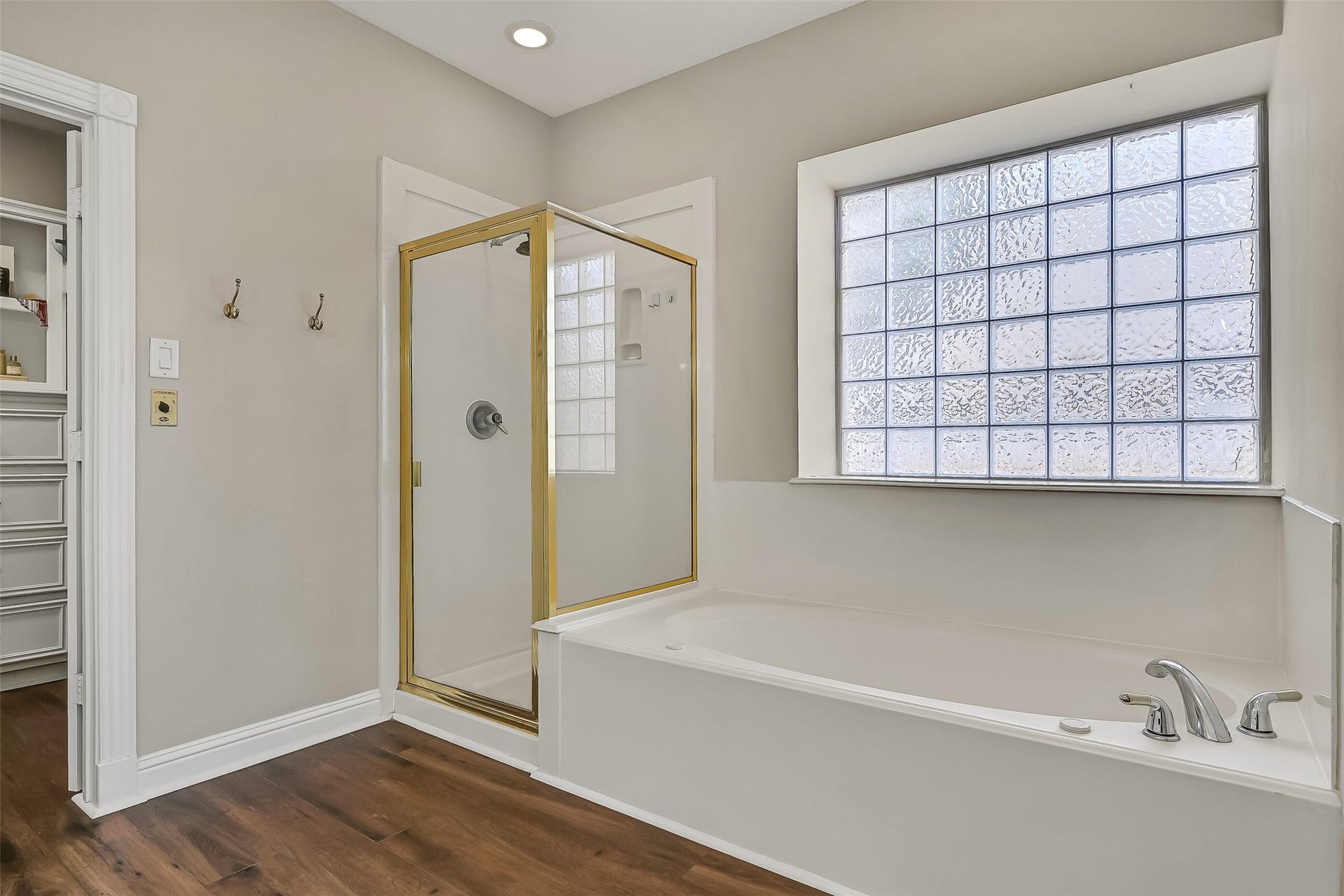 2505 Sarasota Drive, Friendswood, TX 77546 Opposite the vanities, a jetted soaking tub and separate glass-enclosed shower complete the primary bath. A large glass-block window fills the space with natural light while maintaining privacy, and warm LVP flooring carries throughout.