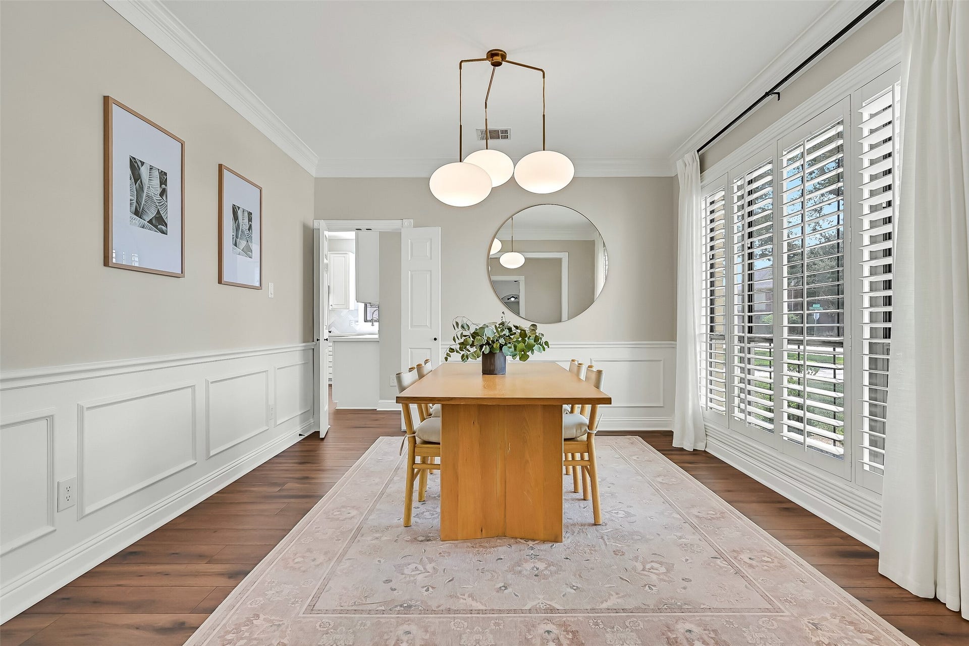 2505 Sarasota Drive, Friendswood, TX 77546 The elegant formal dining room features timeless plantation shutters, crown molding, chair rail & detailed picture-frame millwork. A large front-facing window fills the room with natural light, while LVP flooring provides a seamless transition from the foyer.