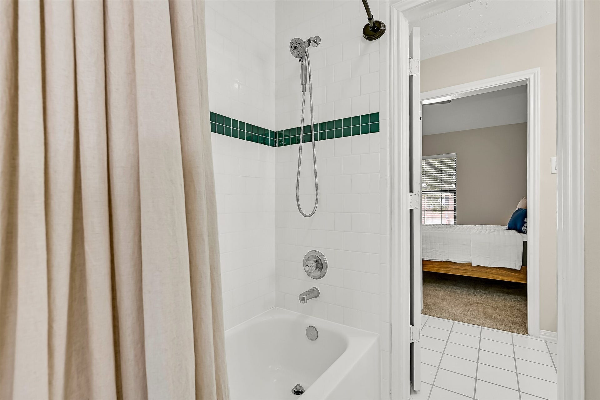2505 Sarasota Drive, Friendswood, TX 77546 At the center of the Jack & Jill bath, a shared tub/shower features crisp white tile with a contrasting accent border, plus both fixed & handheld showerheads. Separate vanity areas on either side create an especially practical setup for the adjoining bedrooms.
