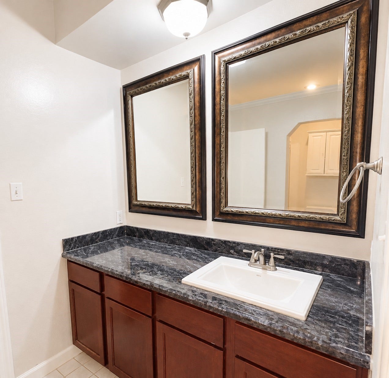 2121 El Paseo Street, #1511, Houston, TX 77054 The bathroom features a spacious vanity countertop, rich wood cabinetry, and decorative framed mirrors, combining a classic look with practical counter space for everyday essentials.
