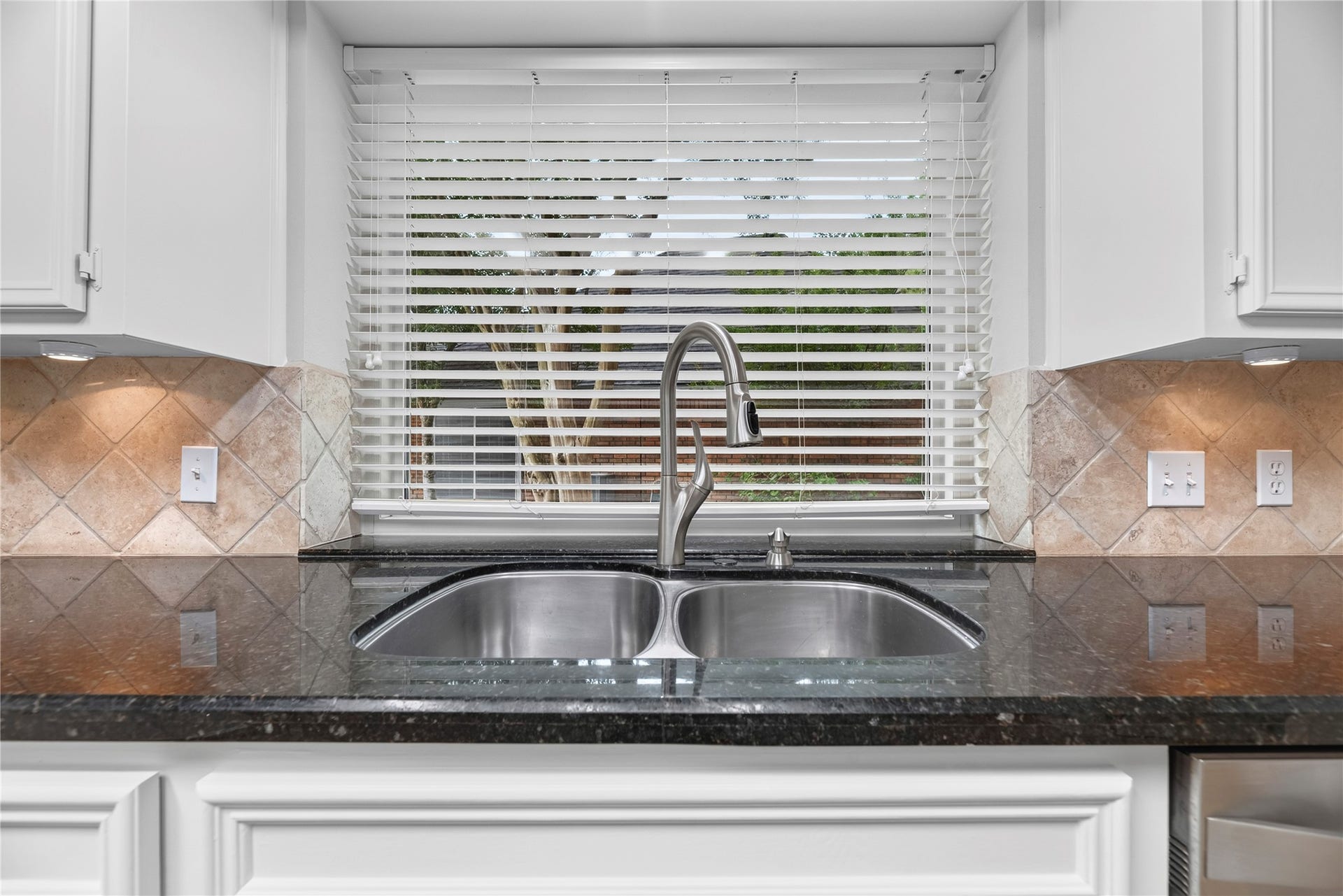 7426 Foxton Place Court, Houston, TX 77095 A double-basin stainless steel sink, sleek granite countertops, tumbled stone backsplash, under-cabinet lighting, an updated window above the sink & bright overhead lighting create a practical workspace for daily kitchen tasks.