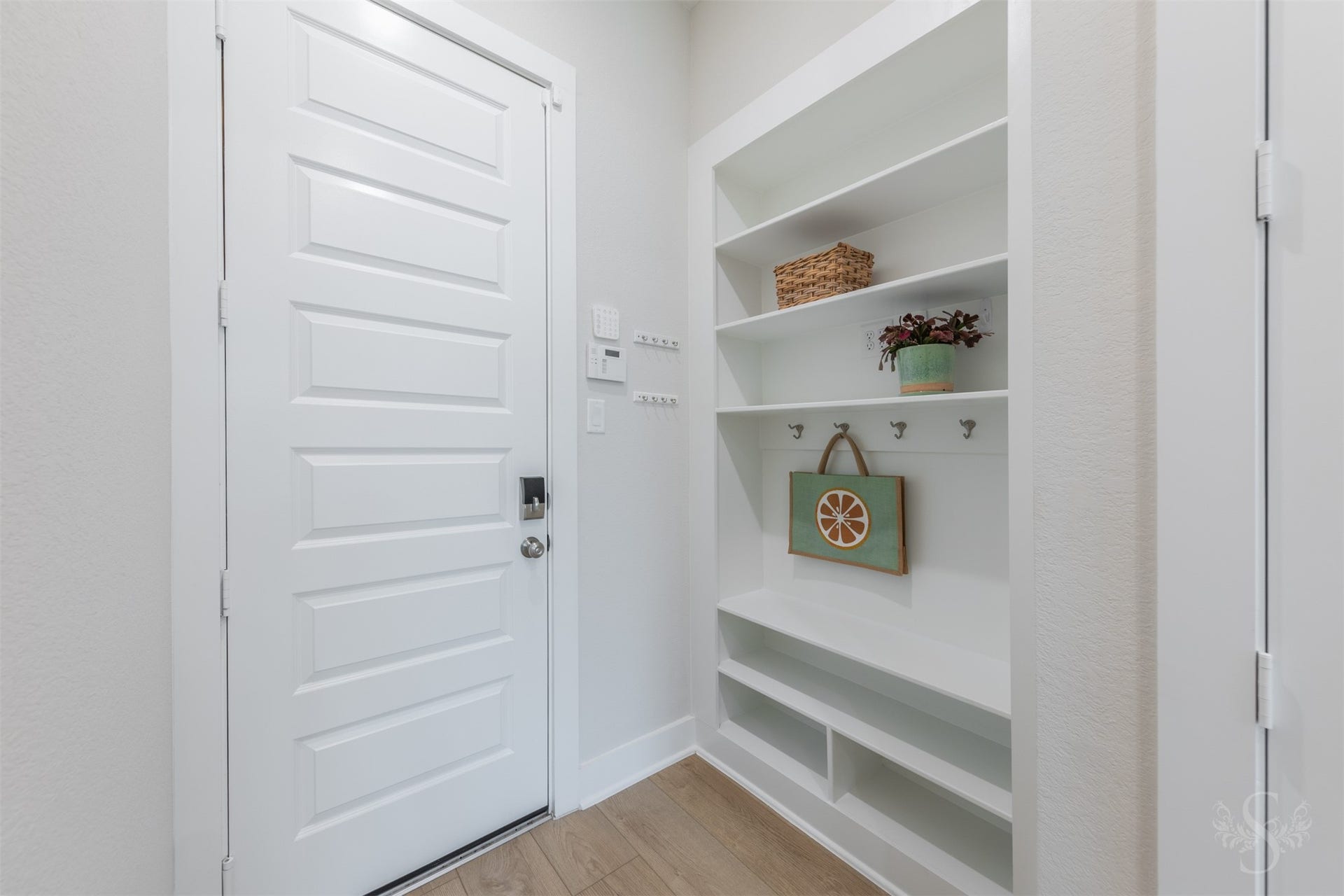 The Mud room provides a beautifully designed place to keep everyday essentials organized. Open shelving, hooks and lower storage add valuable convenience near the homes secondary entrance.