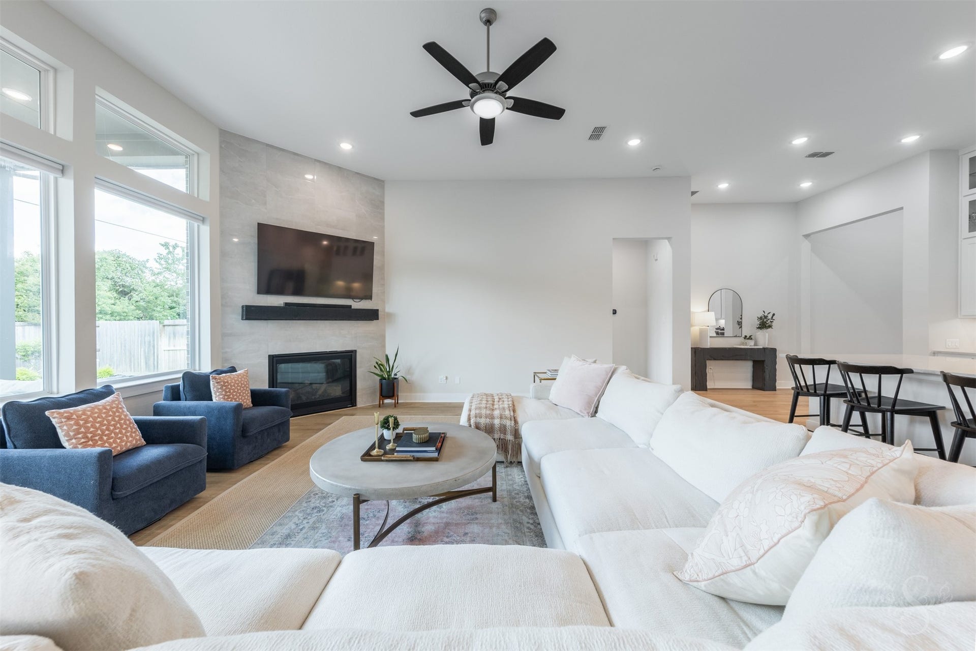 The floor-to-ceiling tiled fireplace creates a striking focal point in this beautifully appointed family room. Expansive windows and the open layout give the space a bright, airy feel.