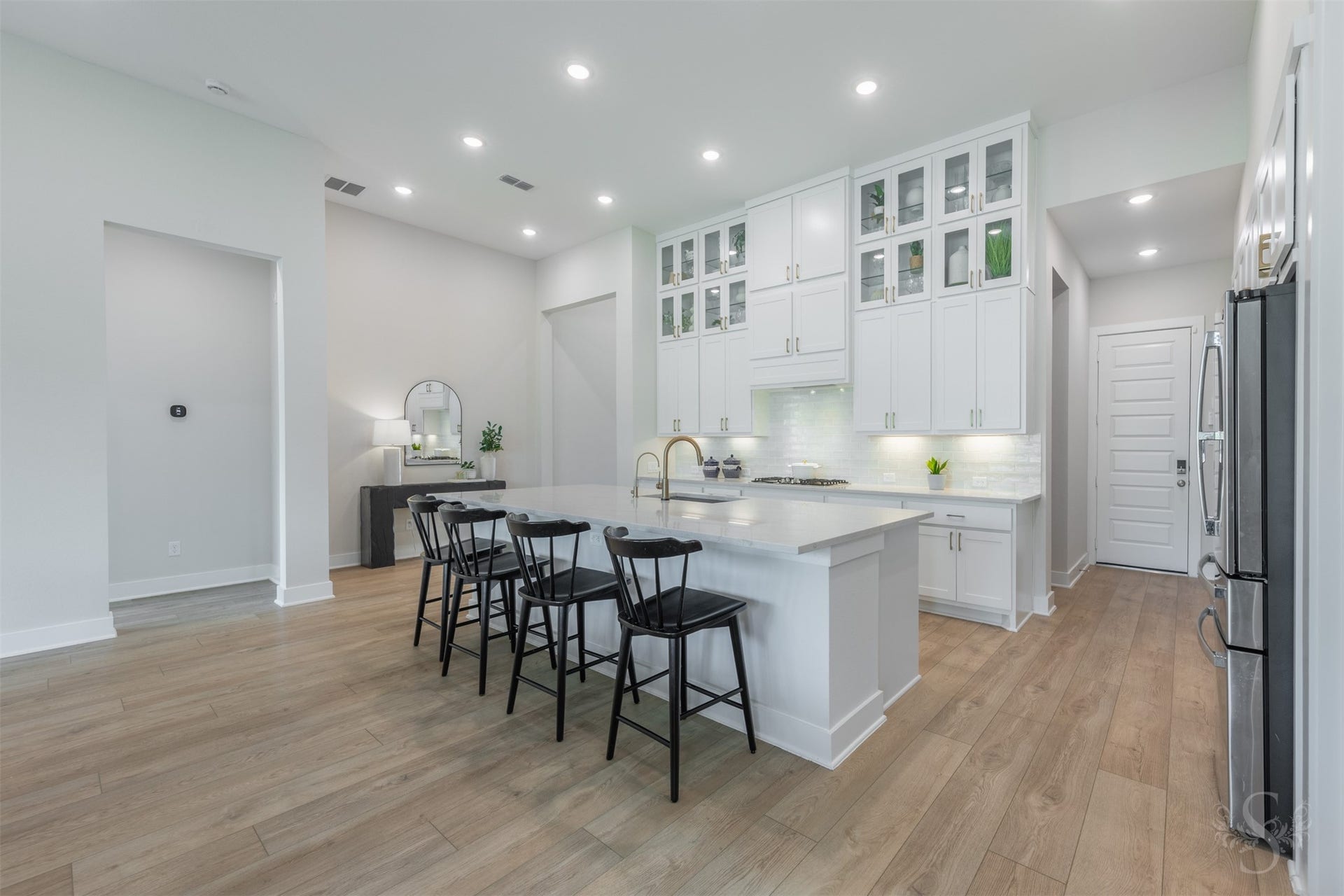 This showstopping kitchen is anchored by an expansive quartz island with breakfast bar. Floor-to-ceiling cabinetry, glass-front displays and warm gold hardware create an unforgettable luxury statement.
