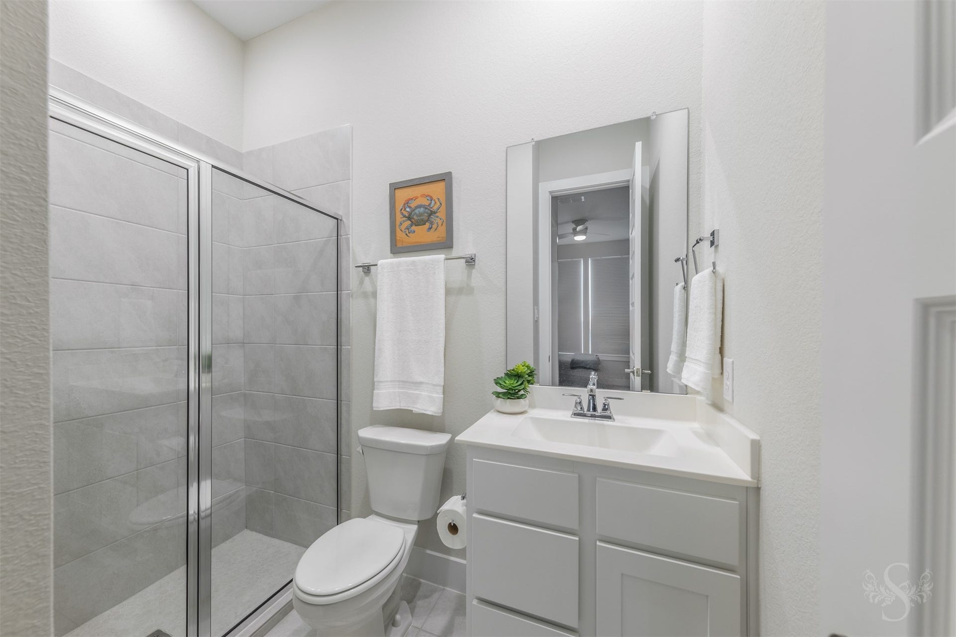 En-suite bath elevates the downstairs guest accommodations with a stylish vanity and beautifully tiled walk-in shower.