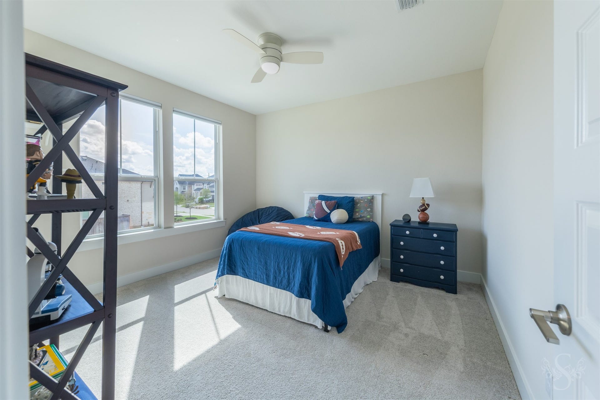Bright upstairs bedroom offers plenty of space for younger family members, with oversized windows bringing in beautiful sunlight. Soft neutral finishes and plush carpeting create a comfortable, inviting retreat.