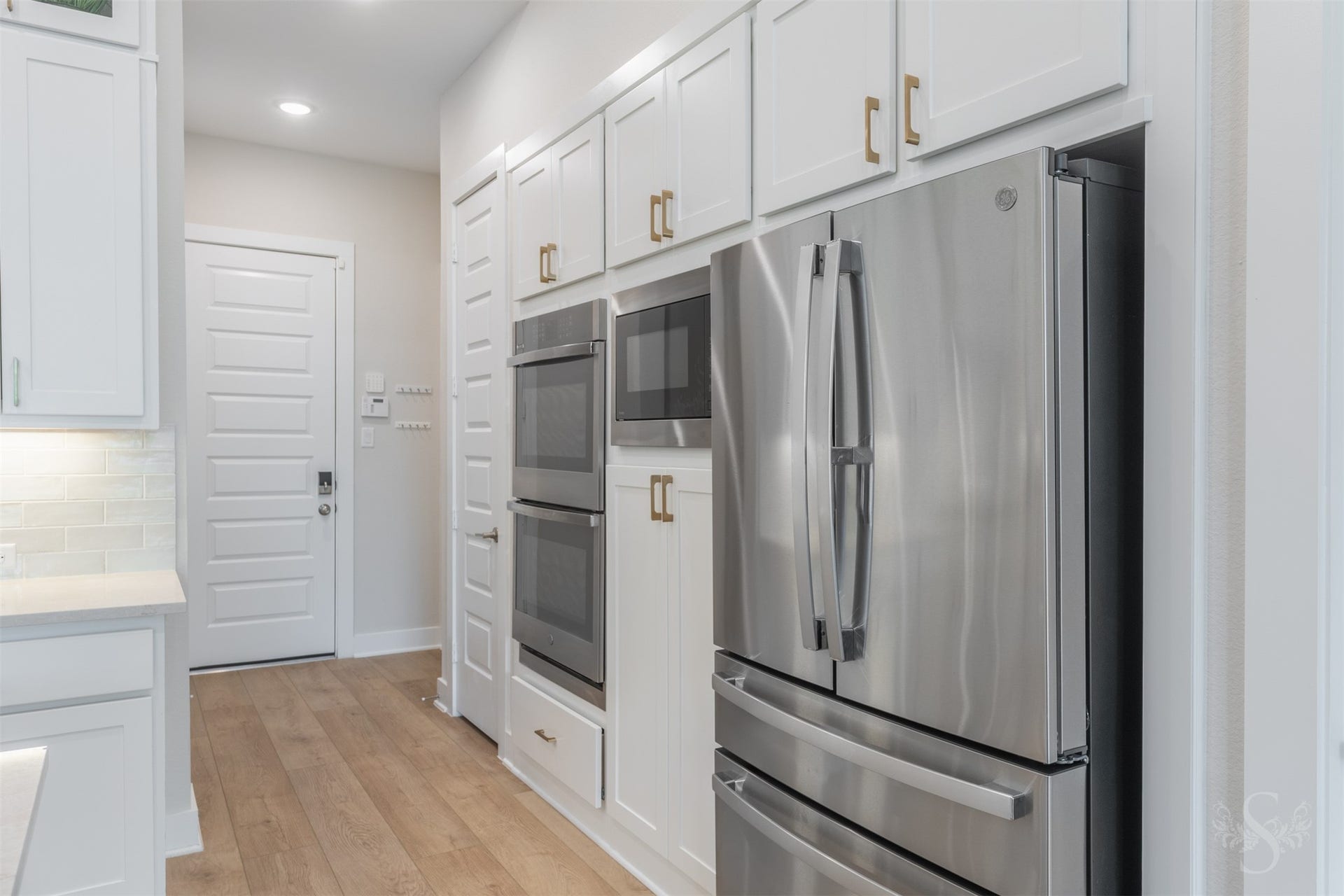 A wall of cabinetry surrounds the stainless steel appliances for a beautifully integrated look. Double ovens provide plenty of cooking space for entertaining family and friends.