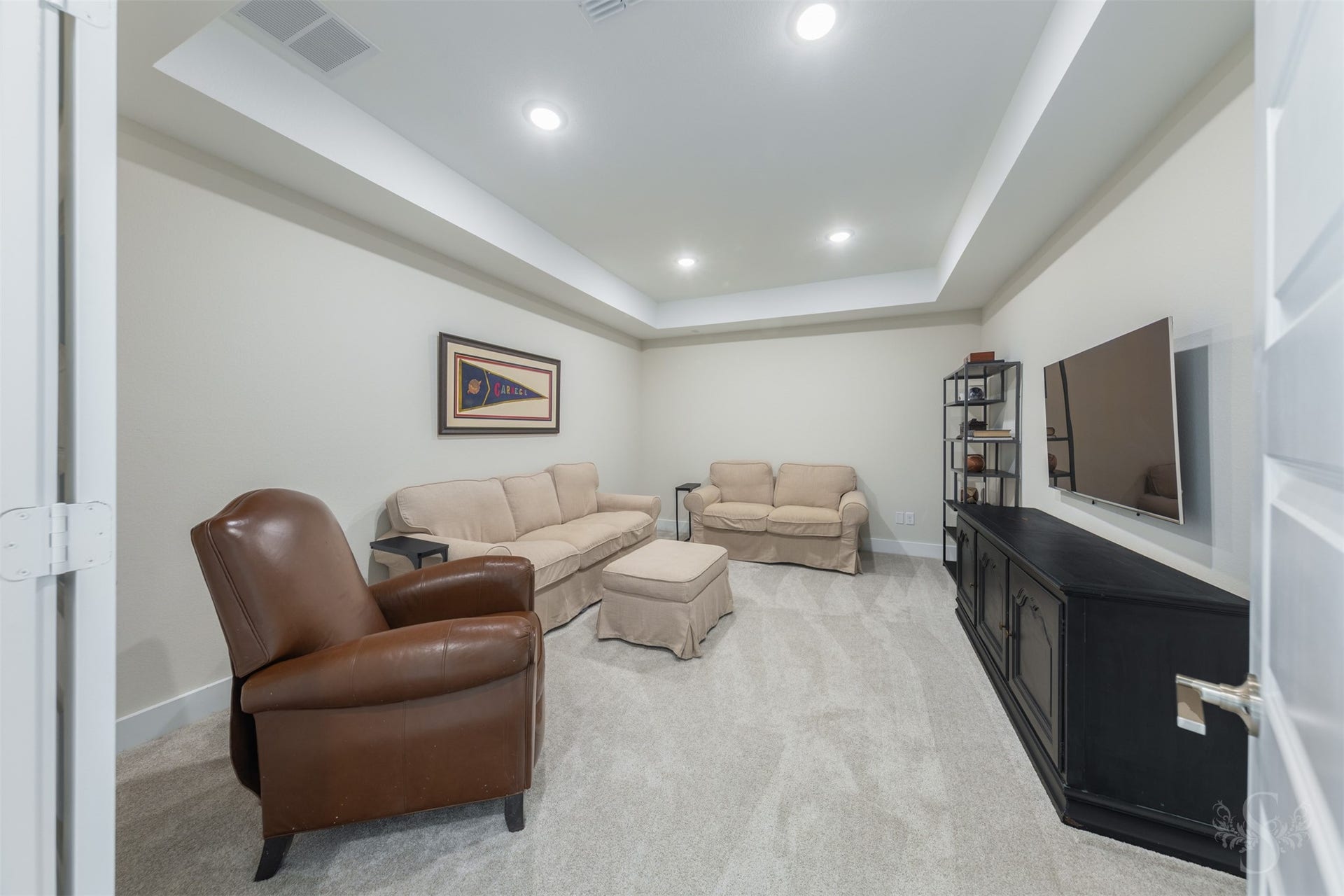 Private media room creates a true cinematic retreat, enhanced by a dramatic tray ceiling and recessed lighting. Spacious layout offers plenty of room for plush theater seating and unforgettable movie nights at home.