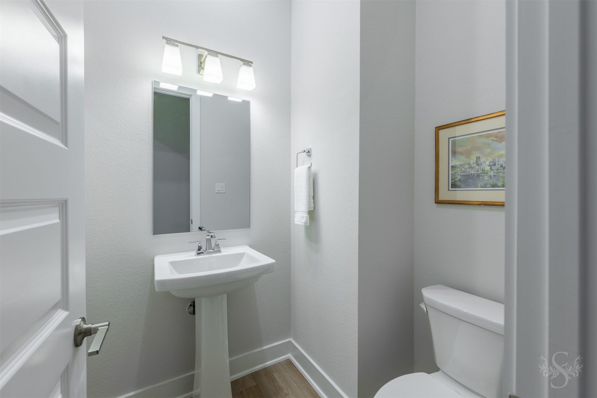 A chic powder bath offers guests a polished space with a pedestal sink, contemporary lighting and crisp modern finishes.