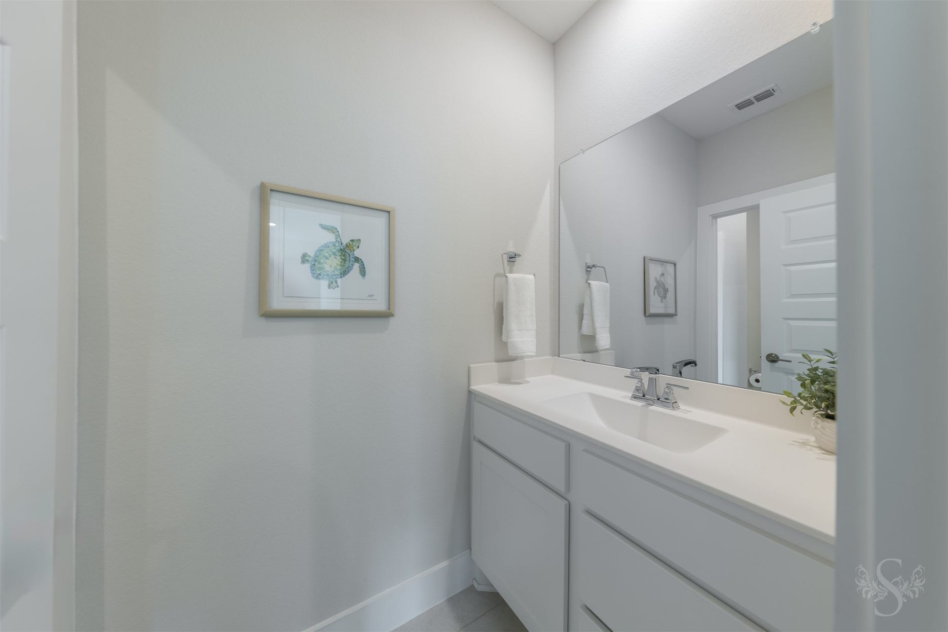 Contemporary secondary bath features a sleek vanity, expansive mirror and crisp finishes that continue the homes modern design.
