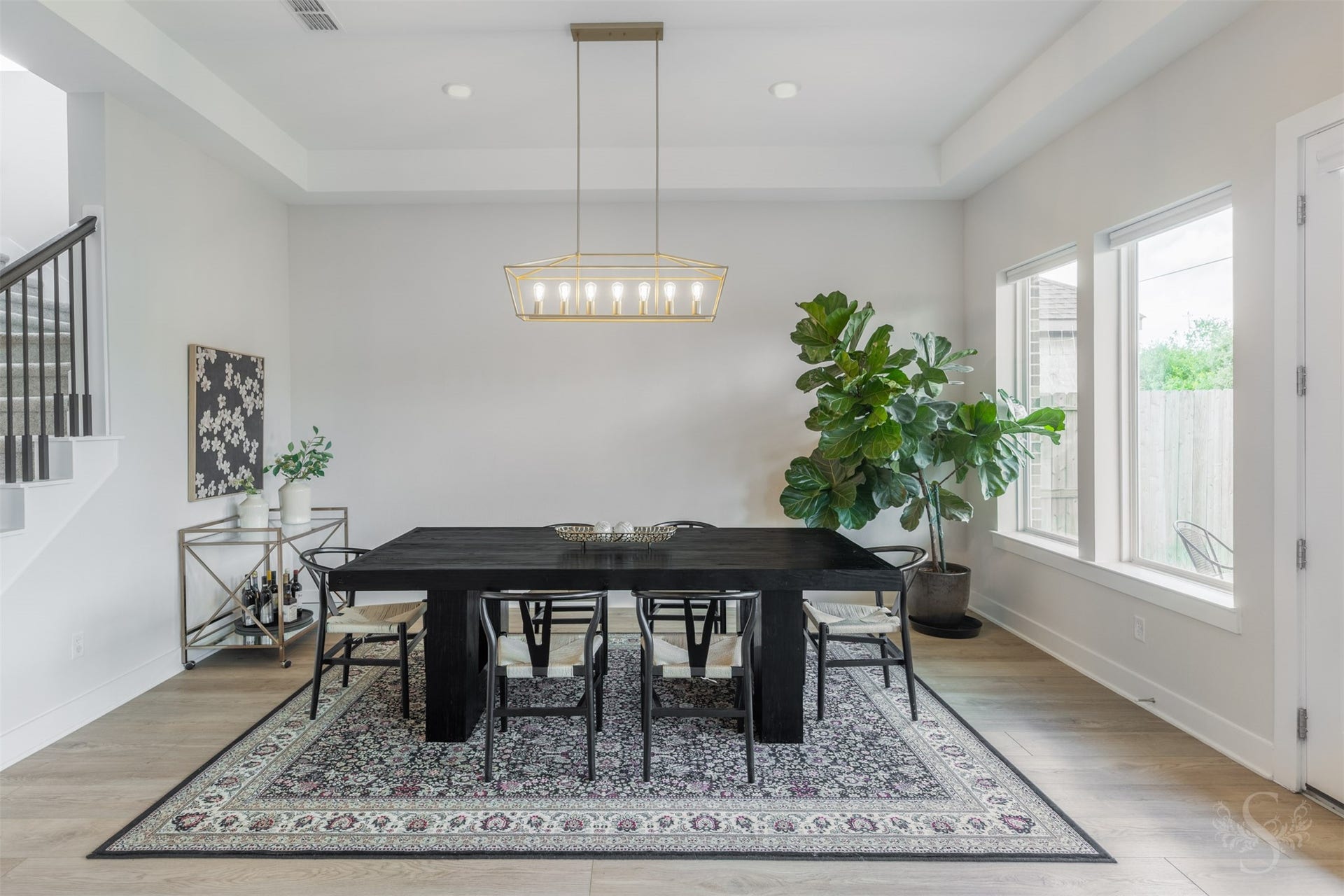 Tray ceiling details and a striking statement chandelier bring a sophisticated touch to the spacious dining area. Large windows create a bright setting for everything from intimate dinners to memorable gatherings.