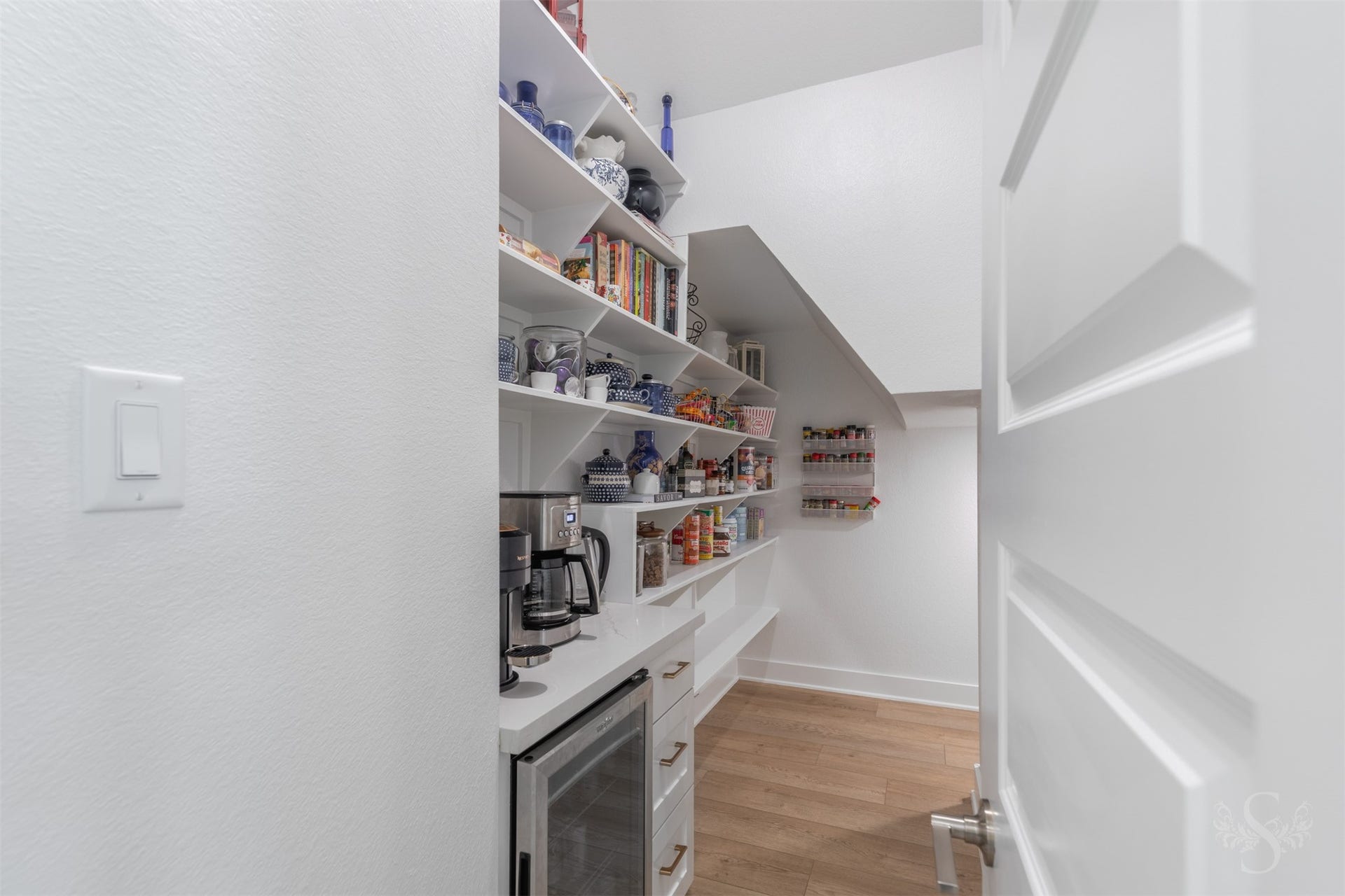 Exceptional walk-in pantry offers an impressive amount of open shelving for organized storage. A quartz counter with cabinetry creates a dedicated space for a mini fridge (stays with home) and beverage preparation.