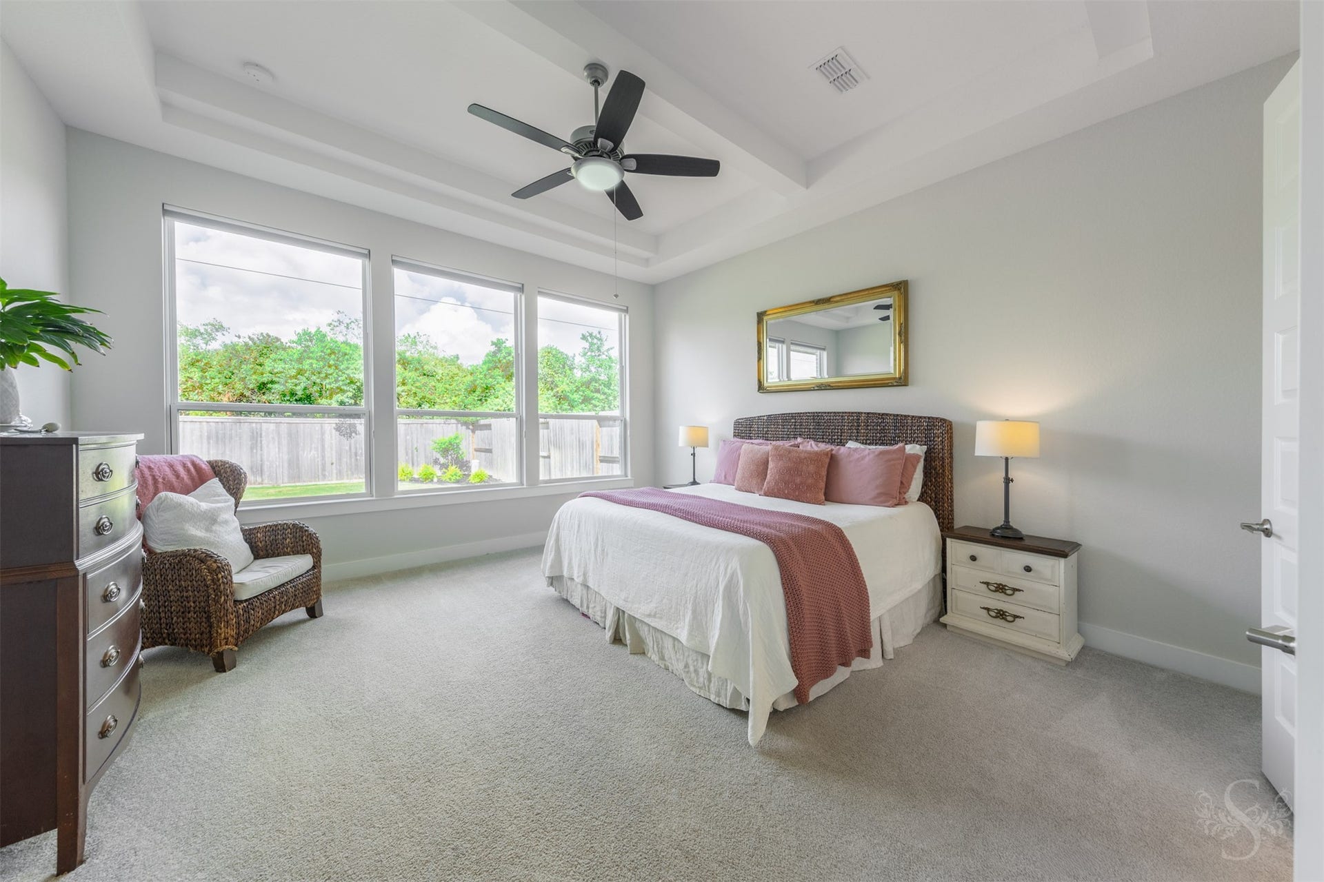 Spacious primary bedroom is beautifully framed by an elegant tray ceiling and a wall of windows overlooking the greenbelt. Plenty of room remains for a sitting area by the windows.
