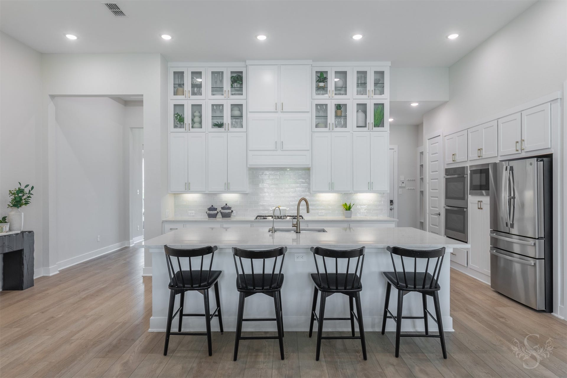 This showstopping kitchen is anchored by an expansive quartz island with breakfast bar. Floor-to-ceiling cabinetry, glass-front displays and warm gold hardware create an unforgettable luxury statement.
