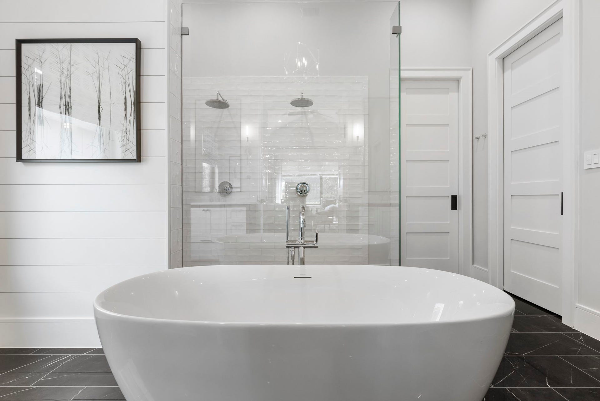 The spa-inspired primary bath features a freestanding soaking tub with a sleek floor-mount filler, set against a dual-head glass-enclosed shower with subway tile.
