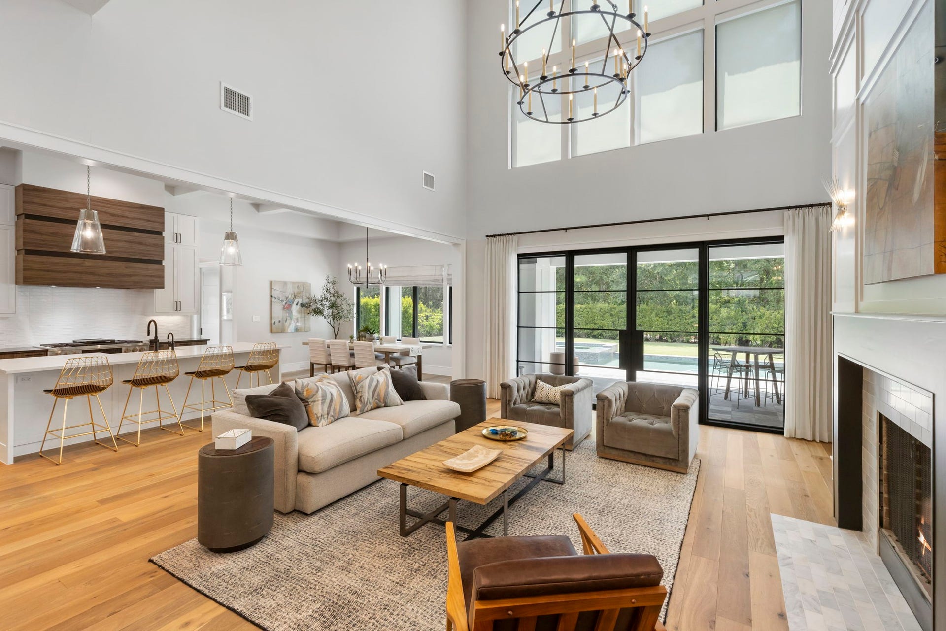 French doors and oversized transom windows above span the wall, framing serene backyard and pool views while flooding the living room with natural light.