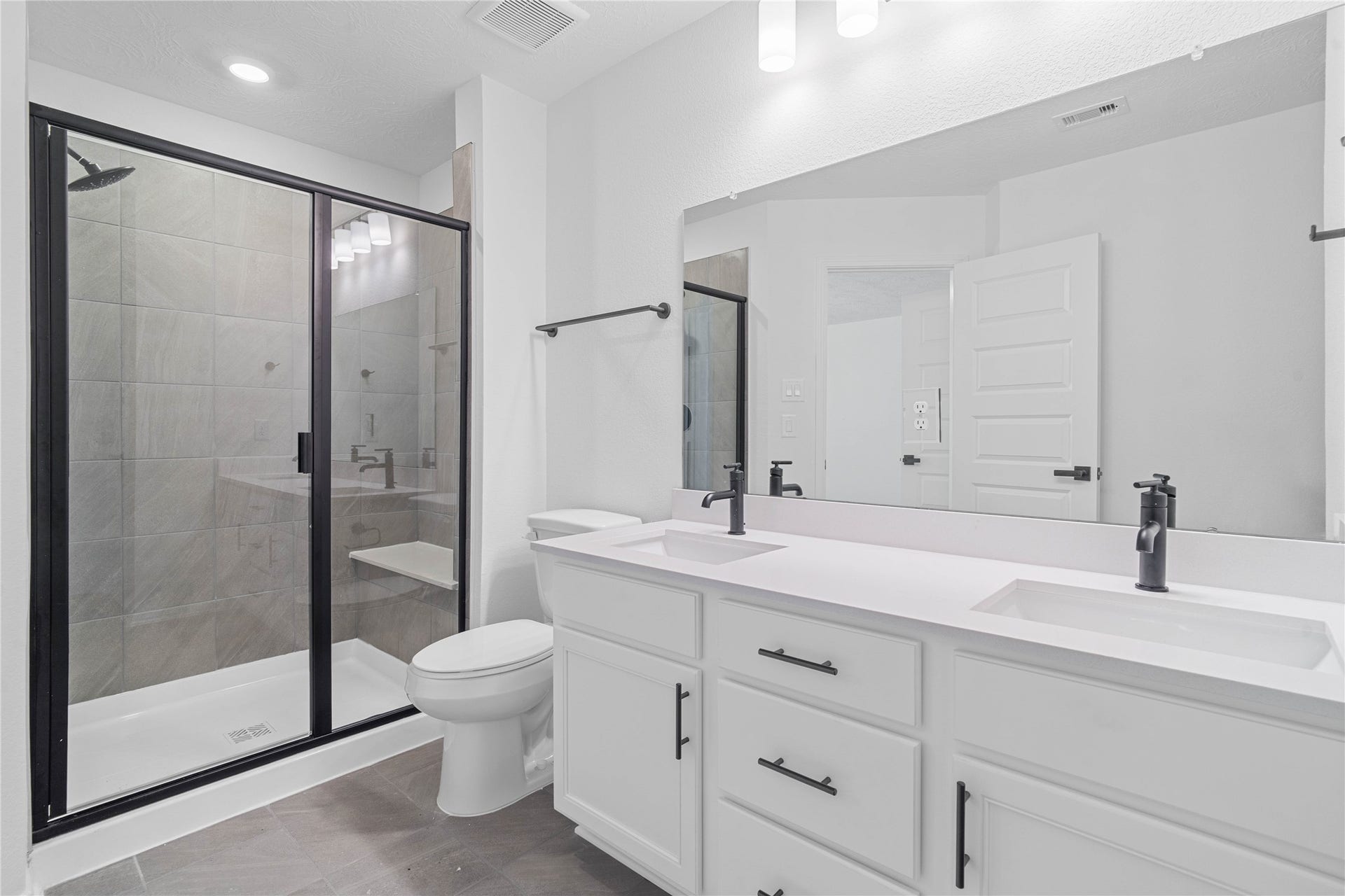 10160 Maple Cove Lane, Willis, TX 77378 The primary bathroom offers a spacious tub/shower combination with a tiled surround, stained cabinetry topped with light countertops, dual sinks, high ceilings, neutral paint, a large mirror, and sleek, modern finishes for a polished look.