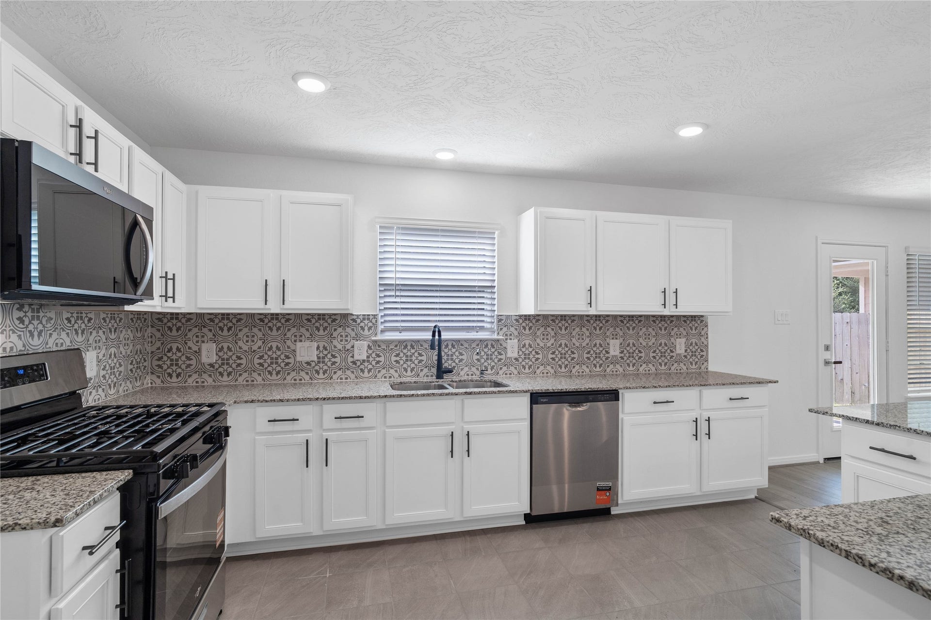 10160 Maple Cove Lane, Willis, TX 77378 This stunning kitchen boasts high ceilings, recessed lighting, Woodmont Belmont cabinets in Espresso stain, quartz countertops, stainless steel Whirlpool appliances, a modern Daltile backsplash, an added breakfast bar, and a pantryall overlooking the expansive Great Room.