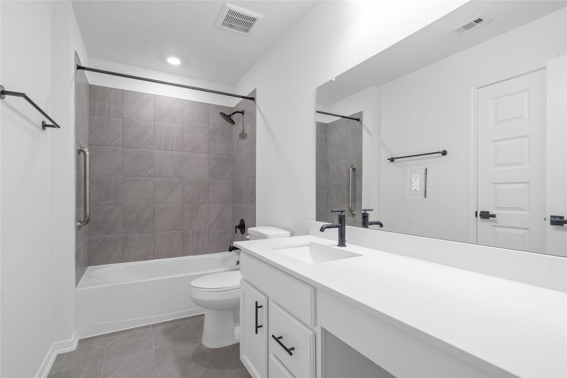 10160 Maple Cove Lane, Willis, TX 77378 The secondary bathroom showcases tile flooring, a bath/shower combo with Daltile tile surround, a vanity with knee space and stunning light countertop, a stylish mirror, sleek fixtures, and contemporary finishes throughout.