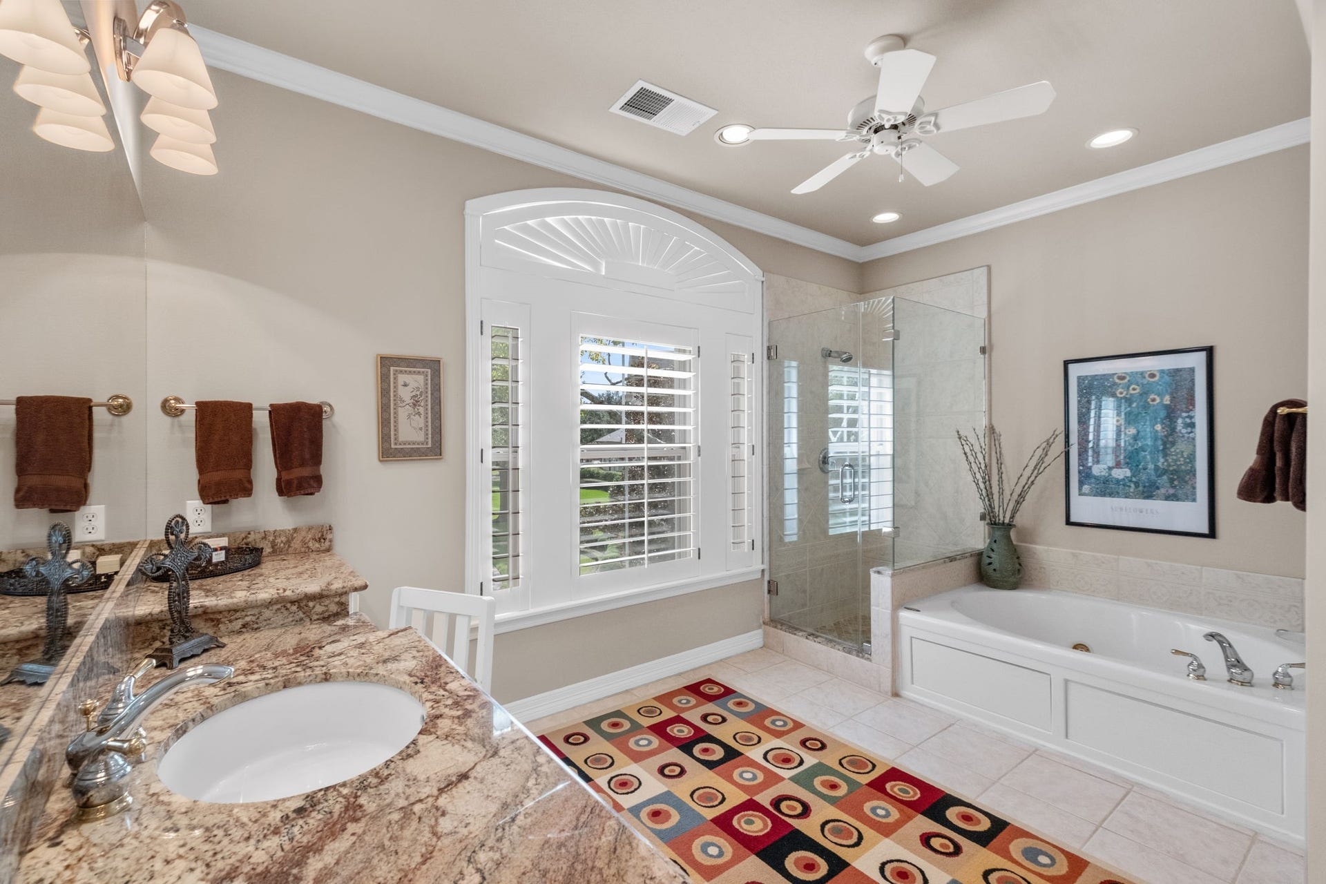 7 Silverloch Court, Sugar Land, TX 77479 Spacious bathroom with elegant granite countertops, a large soaking tub, and a walk-in glass shower, all accentuated by natural light from the arched window.