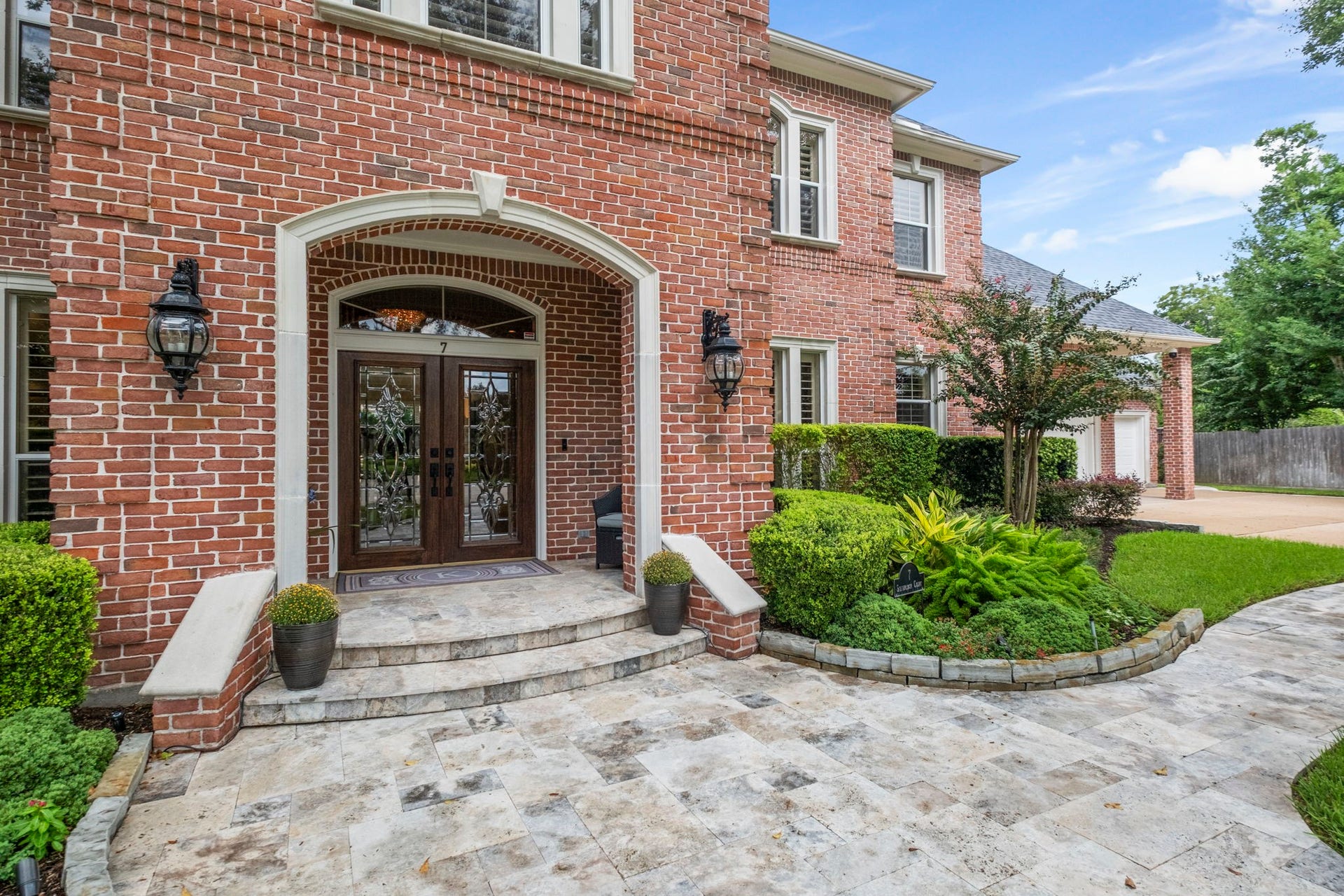 7 Silverloch Court, Sugar Land, TX 77479 Stately brick facade with elegant double doors, framed by lush landscaping and a welcoming stone walkway.