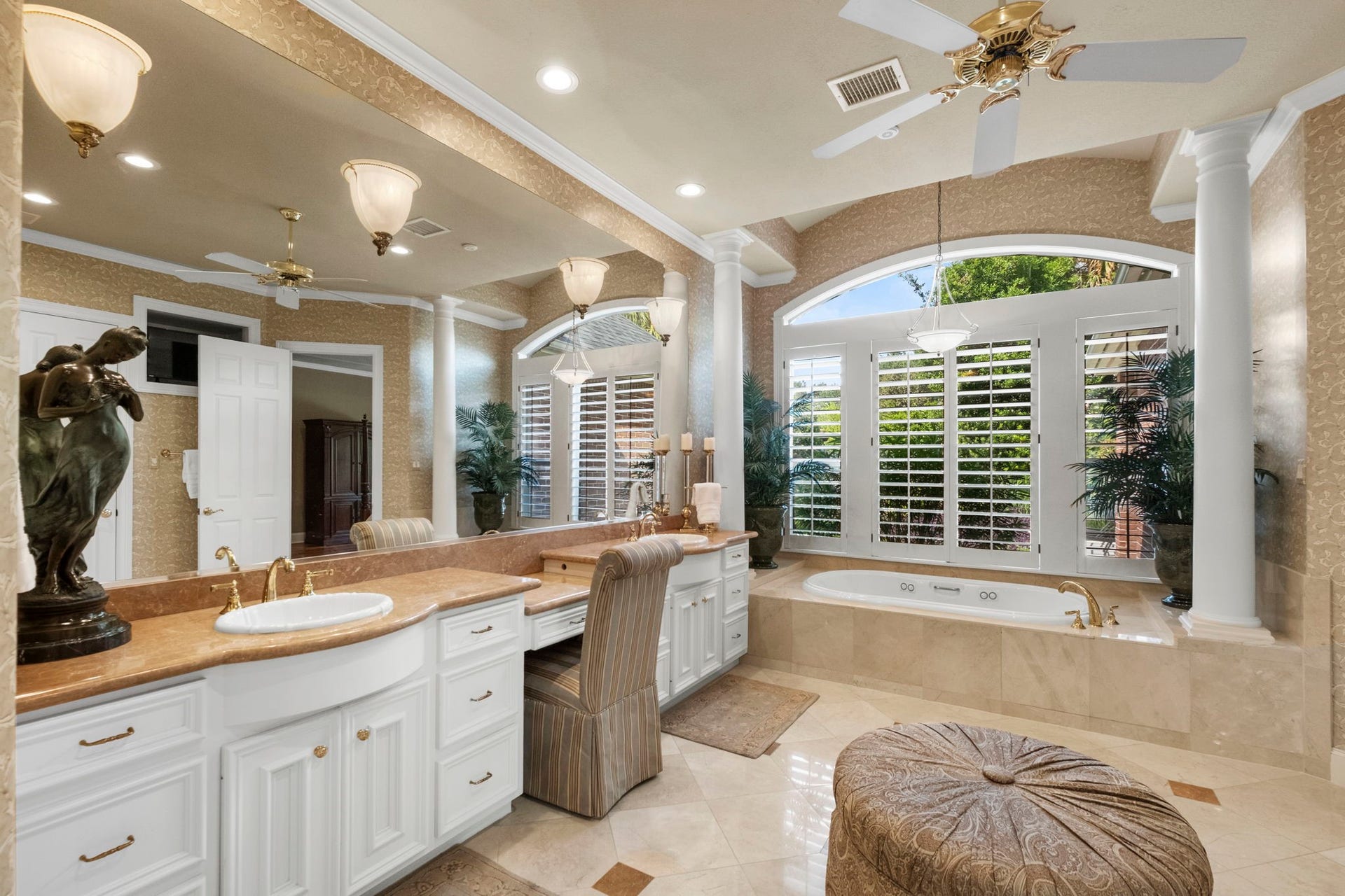 7 Silverloch Court, Sugar Land, TX 77479 Luxurious bathroom featuring a spacious double vanity with elegant fixtures, a relaxing Jacuzzi tub, and large windows with plantation shutters, all enhanced by warm lighting.