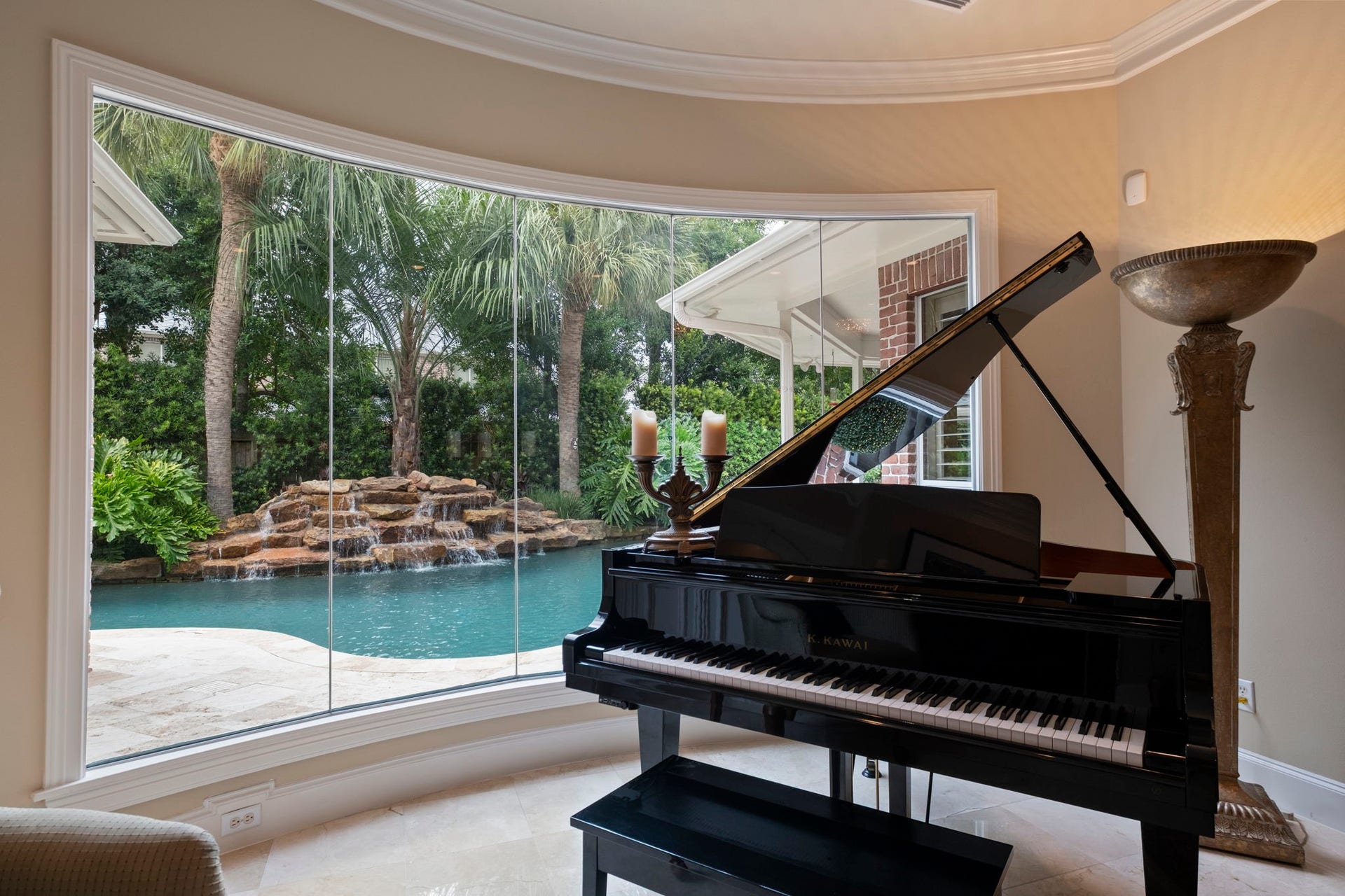 7 Silverloch Court, Sugar Land, TX 77479 Experience serene luxury from the formal living area overlooking a stunning backyard oasis, complete with a sparkling pool and a charming waterfall feature framed by lush greenery.