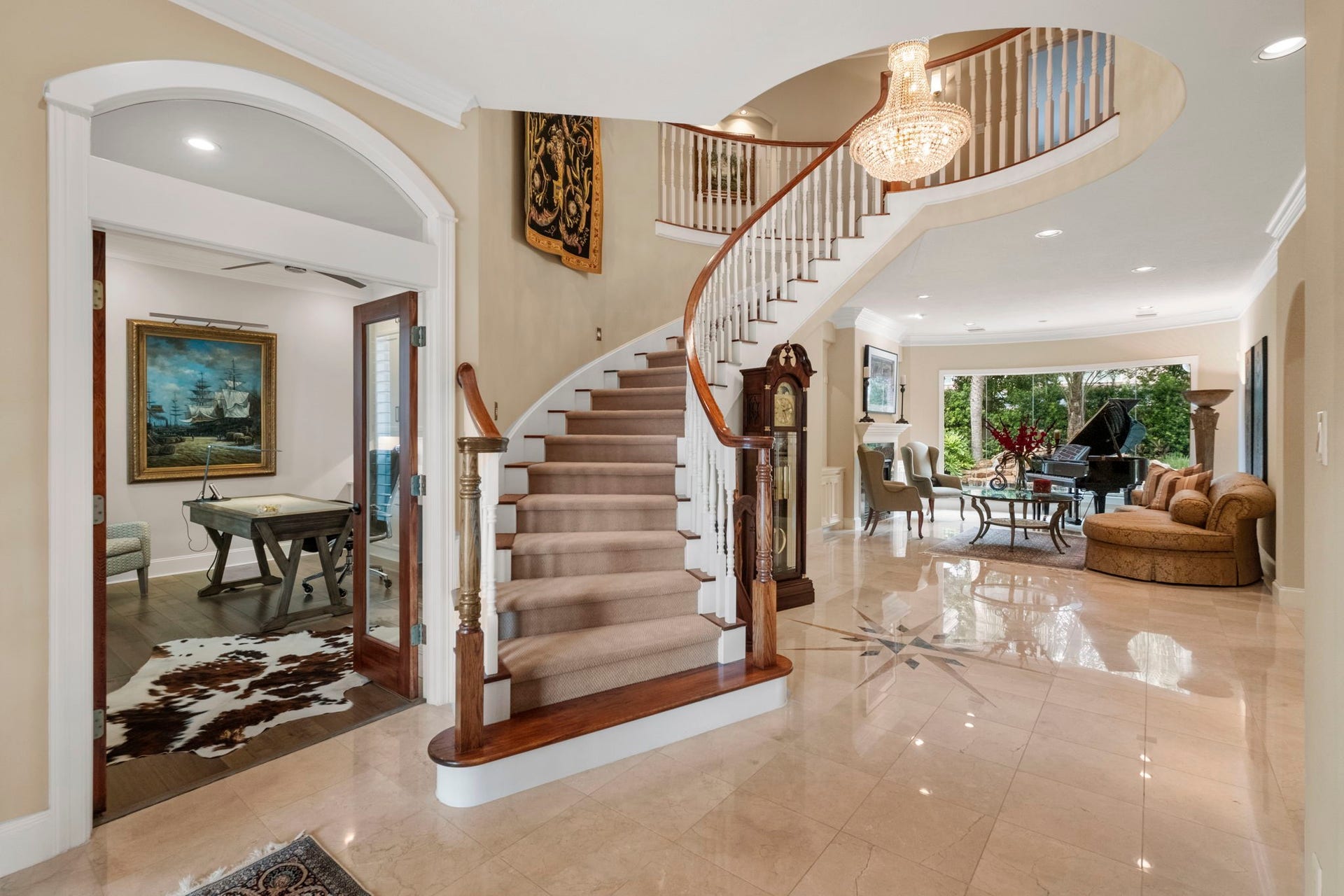 7 Silverloch Court, Sugar Land, TX 77479 A grand foyer with a sweeping curved staircase, elegant Schonbek chandelier, and gleaming marble floors leads to a spacious living area with large windows overlooking the pool.