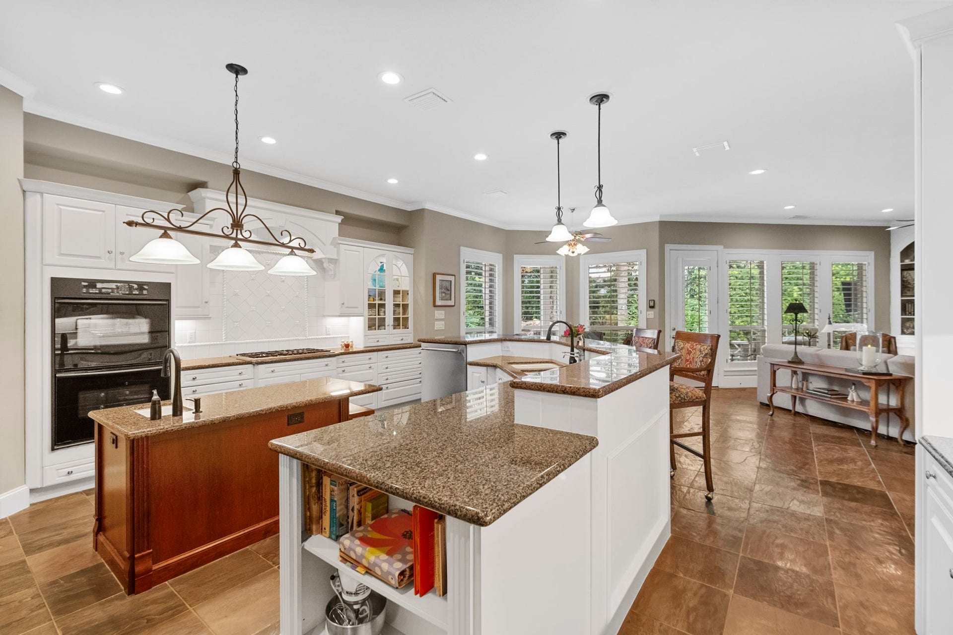 7 Silverloch Court, Sugar Land, TX 77479 Spacious kitchen with elegant granite countertops, a large center island with an extra sink, and abundant natural light from surrounding windows. The water filter system at Kitchen sink is Tyent Retten Water Ionizer.