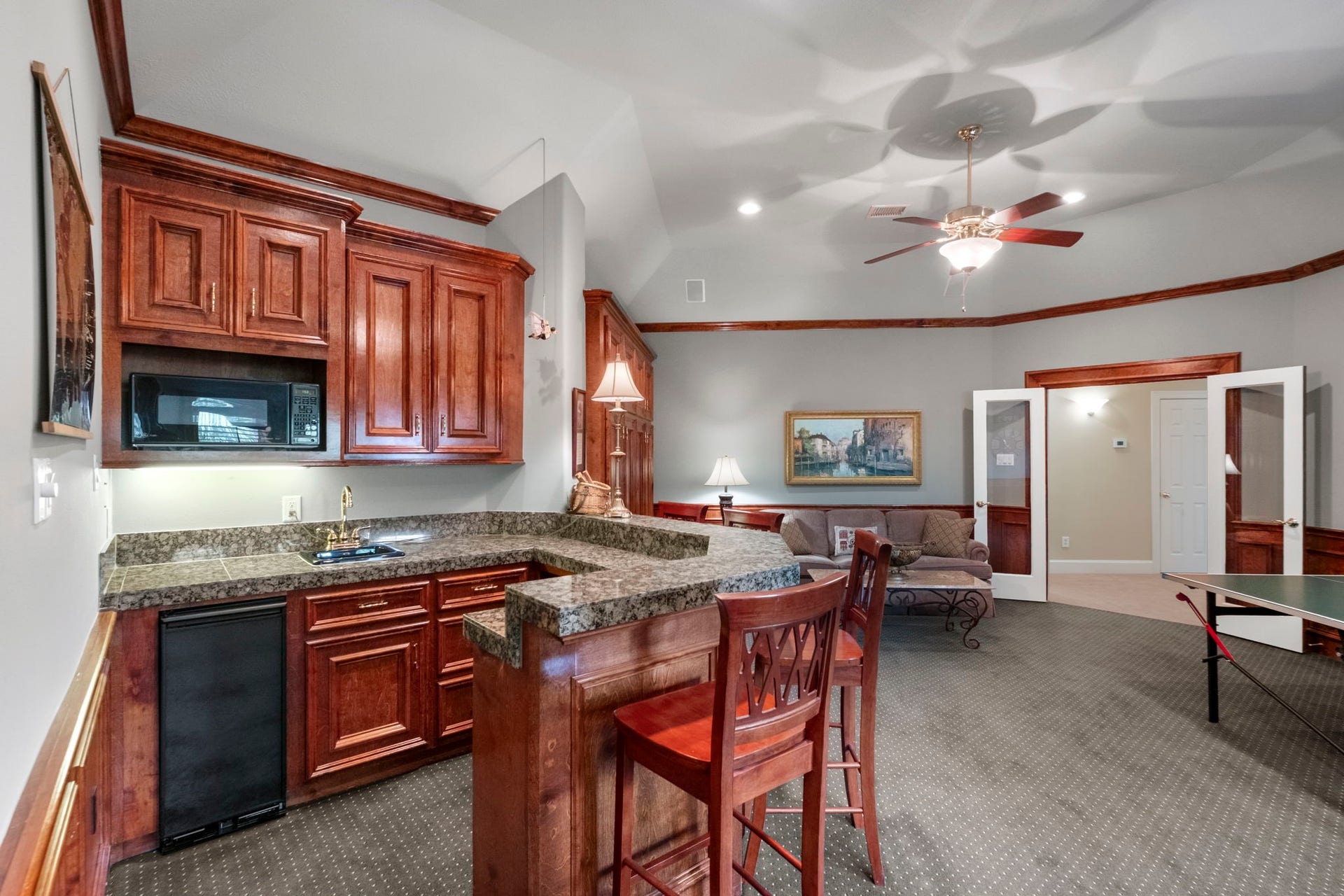 7 Silverloch Court, Sugar Land, TX 77479 Spacious entertainment room featuring a cozy sitting area, elegant wet bar with rich wood cabinetry, and an adjacent game space perfect for leisure and gatherings.
