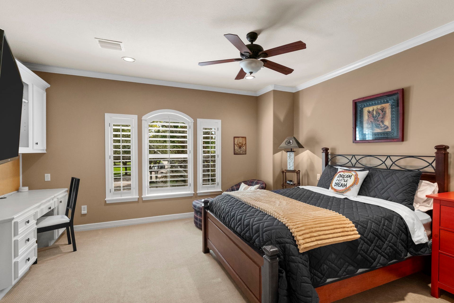 7 Silverloch Court, Sugar Land, TX 77479 Spacious bedroom with warm tones features large windows with shutters, a ceiling fan, and a built-in desk area, offering comfort and functionality.
