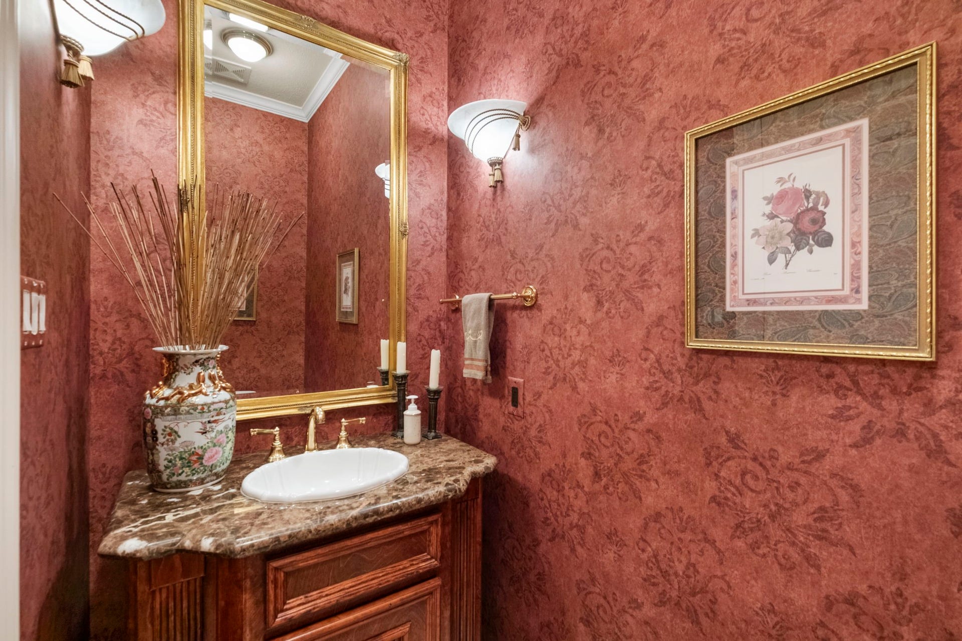 7 Silverloch Court, Sugar Land, TX 77479 Elegant powder room featuring rich red textured wallpaper, a marble countertop, and a decorative gold-framed mirror, offering a luxurious touch.