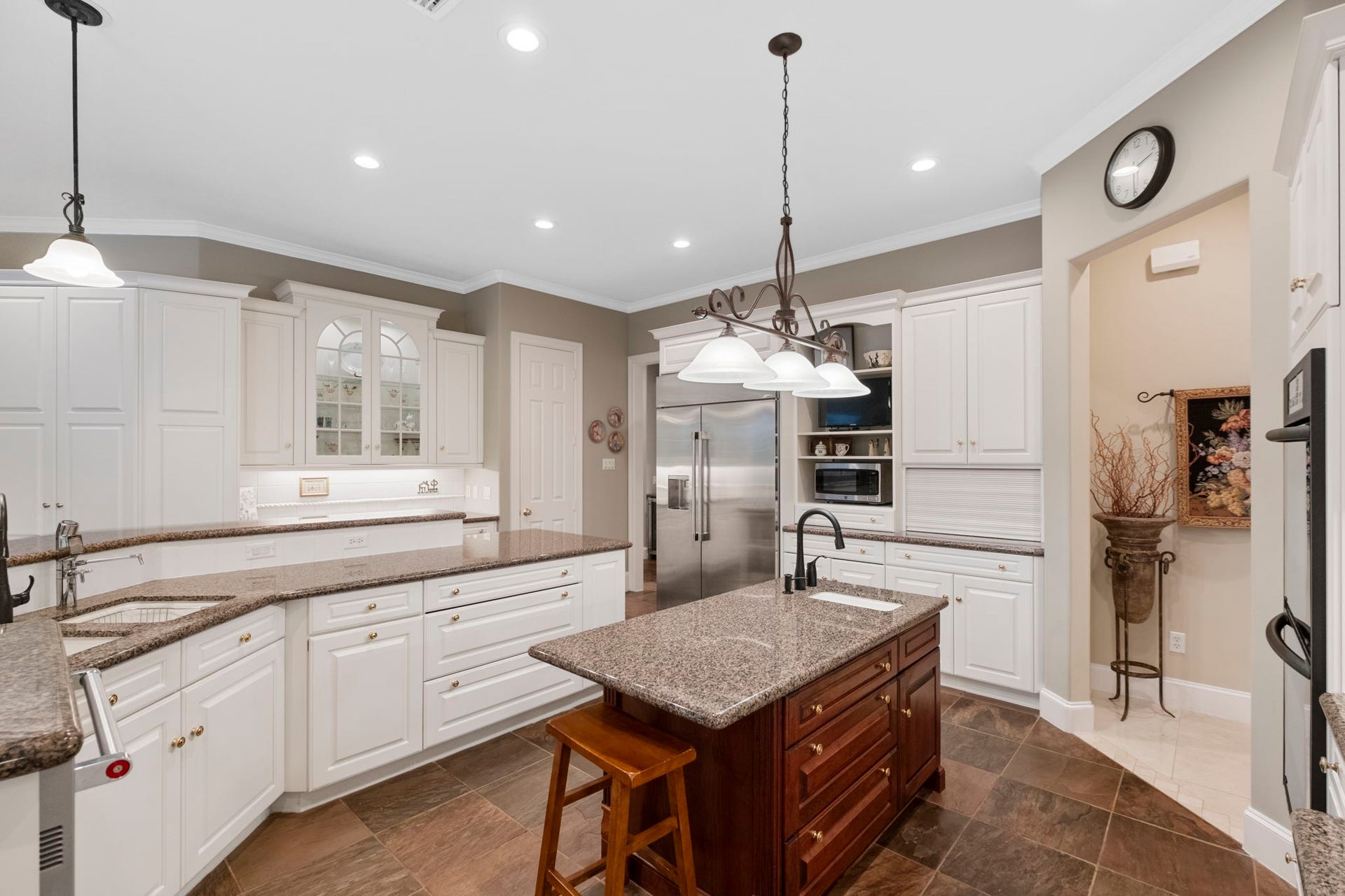 7 Silverloch Court, Sugar Land, TX 77479 Spacious kitchen with elegant granite countertops, a central island, and ample white cabinetry, complemented by modern appliances and stylish lighting fixtures.