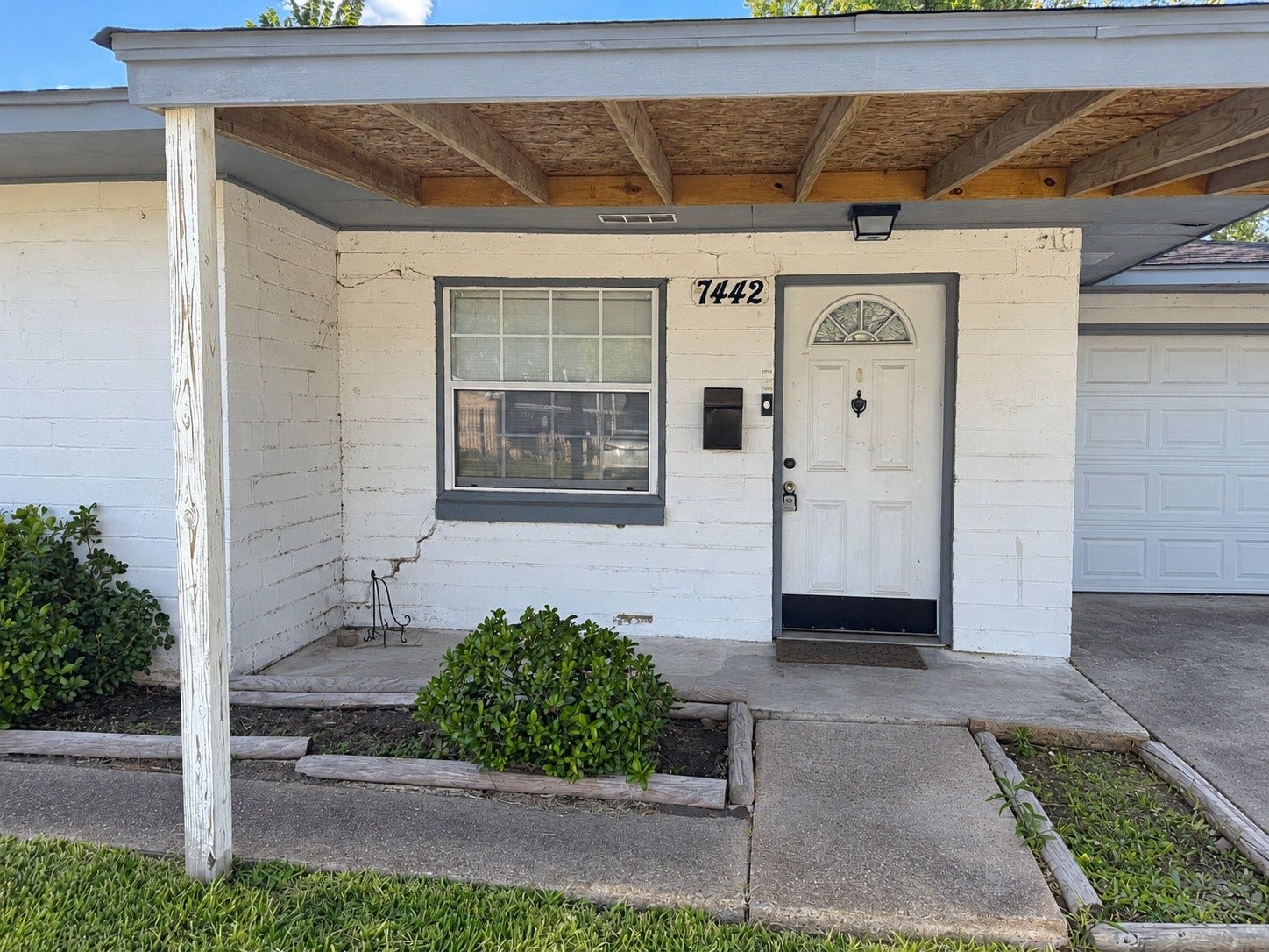 7442 Allsup Street, Houston, TX 77061 Covered front entry with a fresh white exterior and tidy landscaping.
