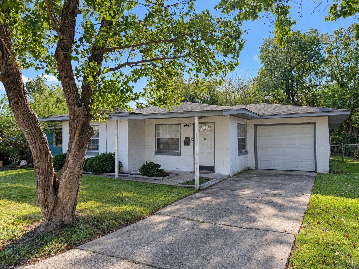 7442 Allsup Street, Houston, TX 77061 Long driveway leads to a one-car garage, with mature shade trees in front.