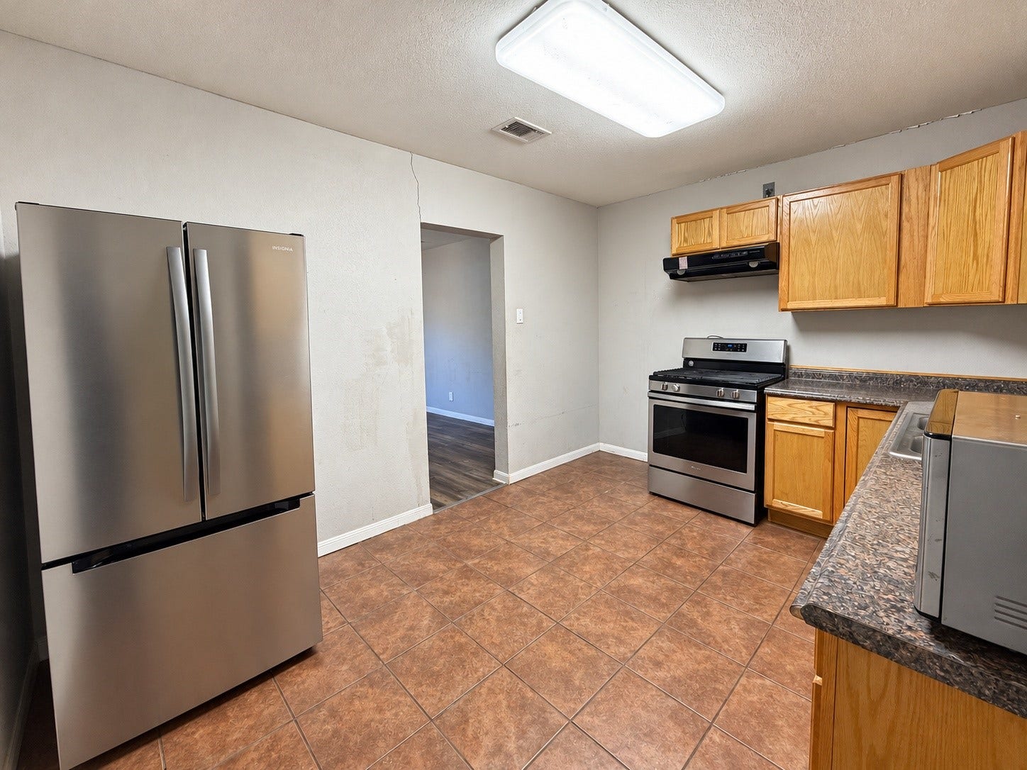 7442 Allsup Street, Houston, TX 77061 Kitchen with a stainless refrigerator, range and microwave, plus easy-care tile floors.