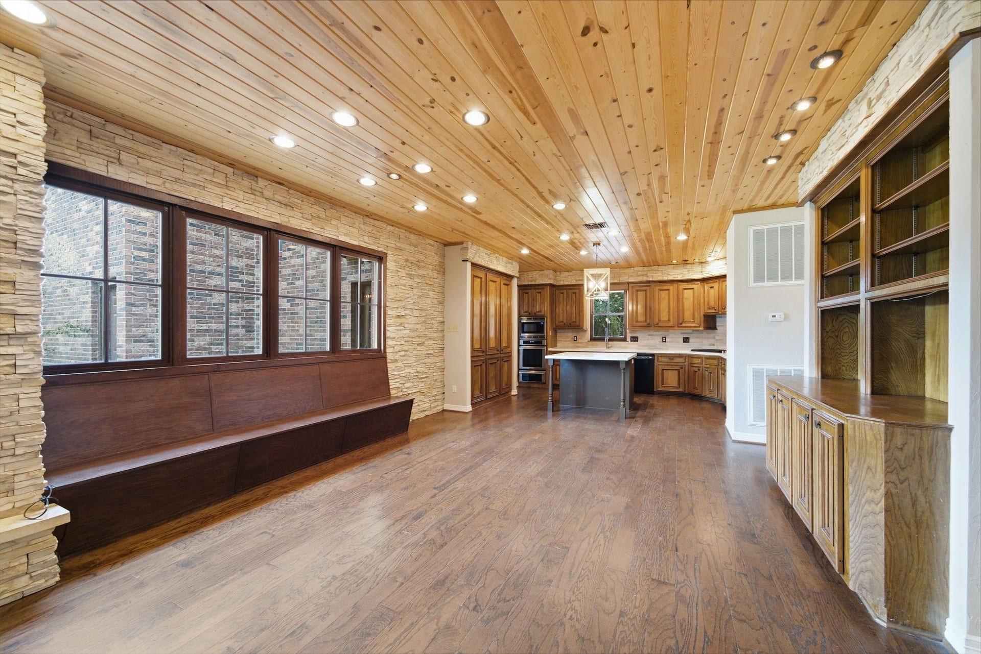 Stunning rustic kitchen and dining area with rich wood finishes, stone accents, and built-in seating. Abundant natural light and spacious layout make it perfect for entertaining.
