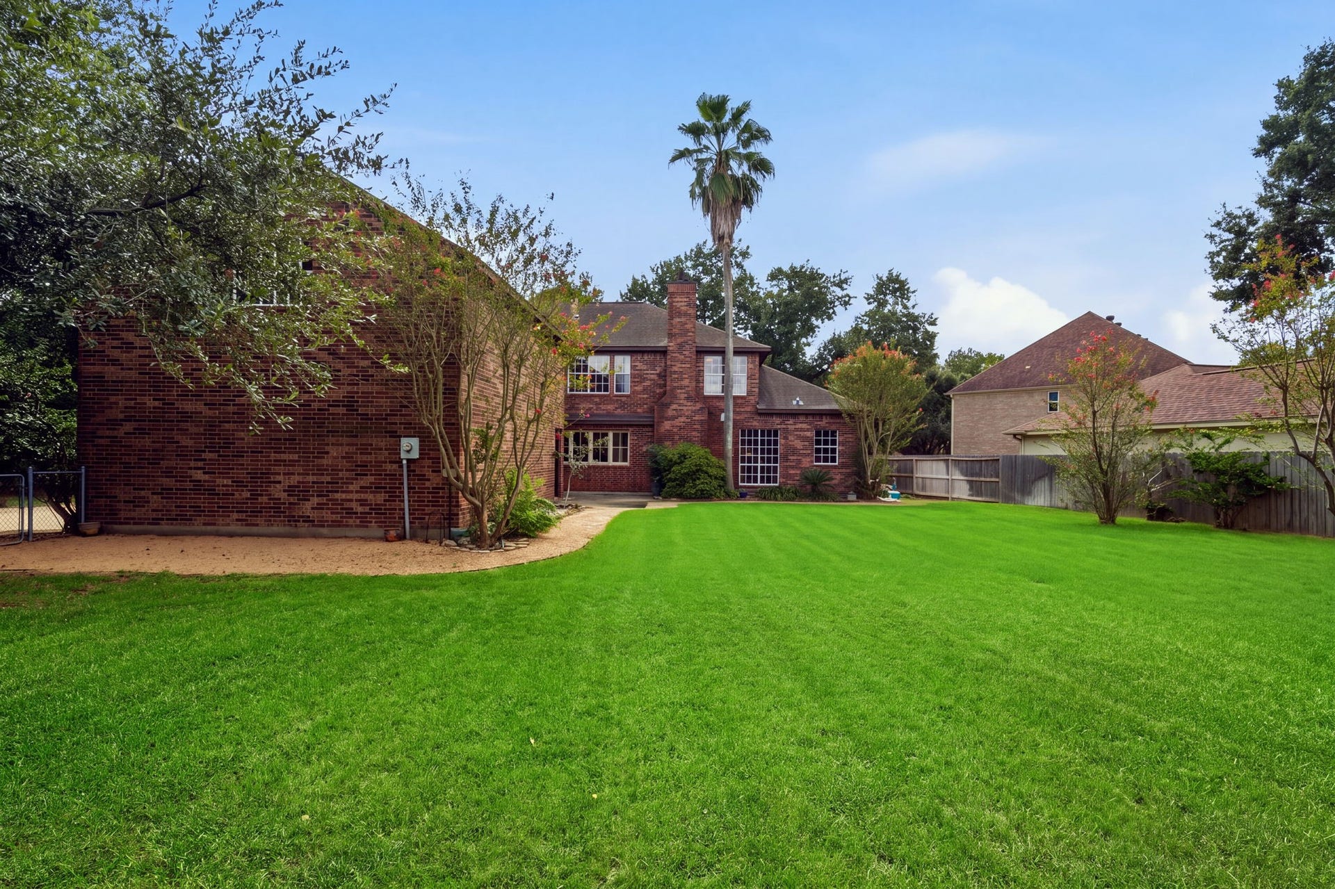 Expansive backyard with lush lawn and mature trees, complemented by a charming brick exterior.
