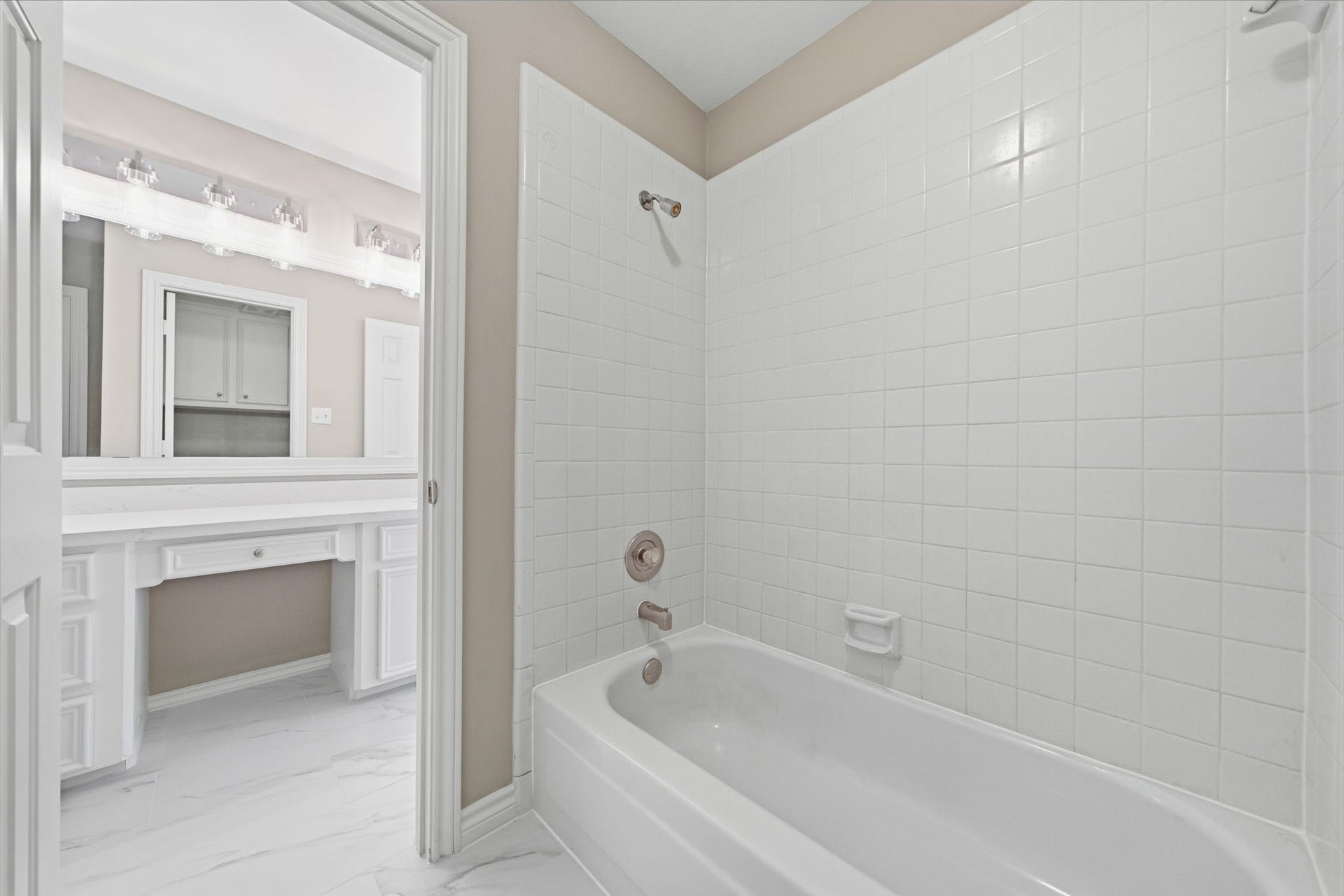 The adjoining tub and shower area is finished in classic white tile for a timeless look. Ample storage makes the bathroom as functional as it is bright.